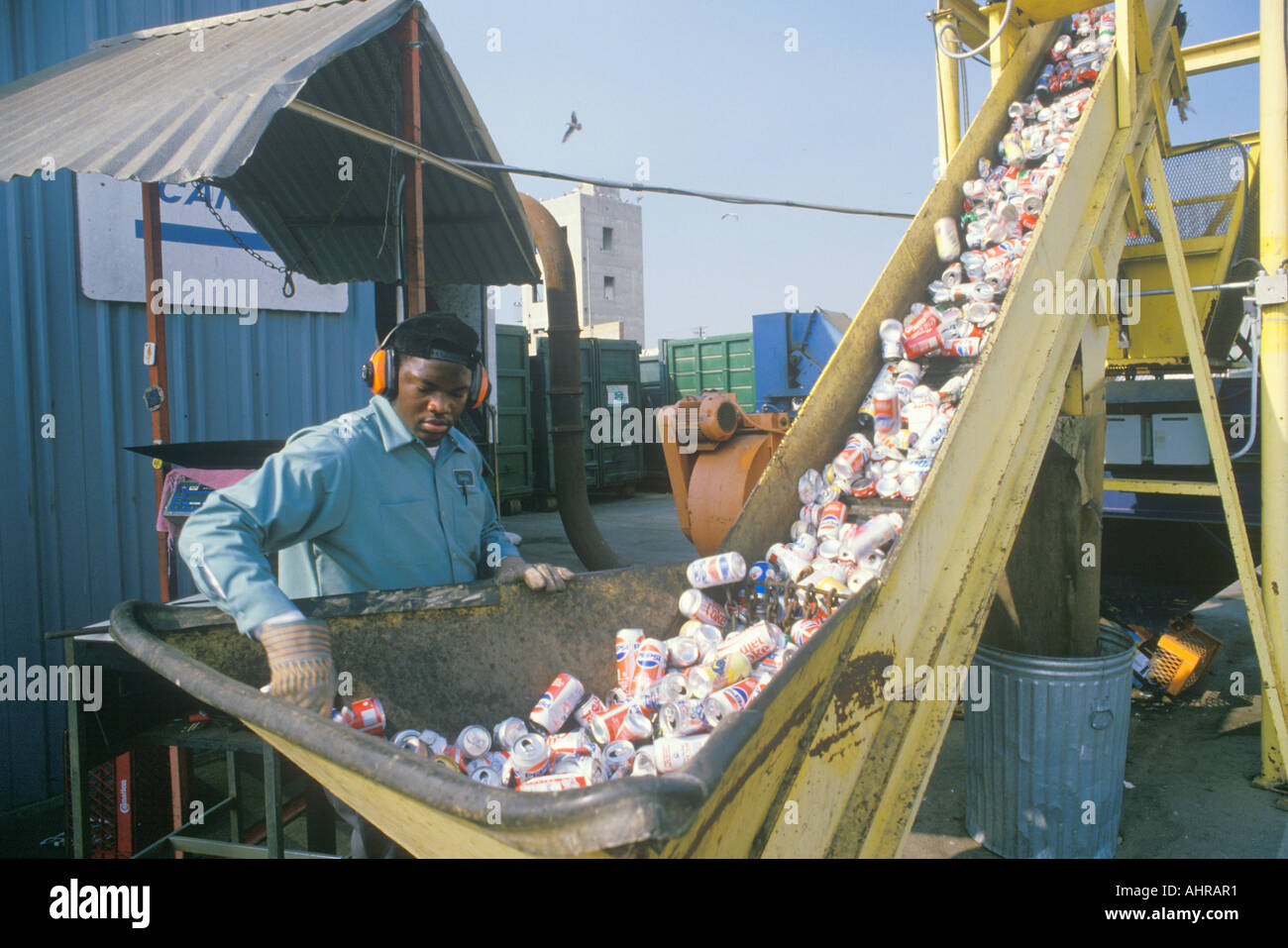 Un trabajador supervisar las latas de aluminio que se mueve a lo largo de un transportador en un centro de reciclaje en Santa Mónica, CA Foto de stock