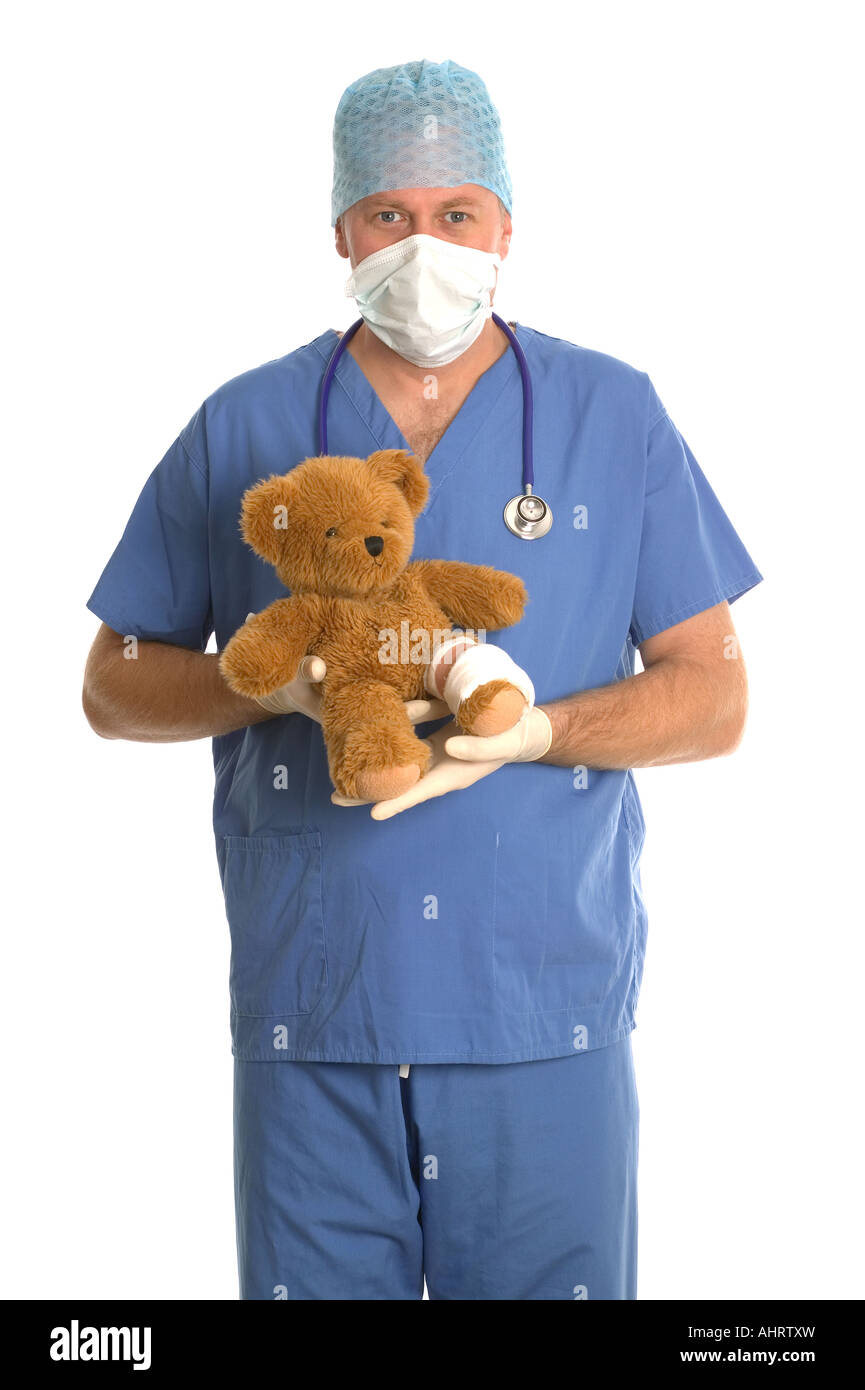 Cirujano en scrubs sosteniendo un oso de peluche con una pierna vendada Foto de stock