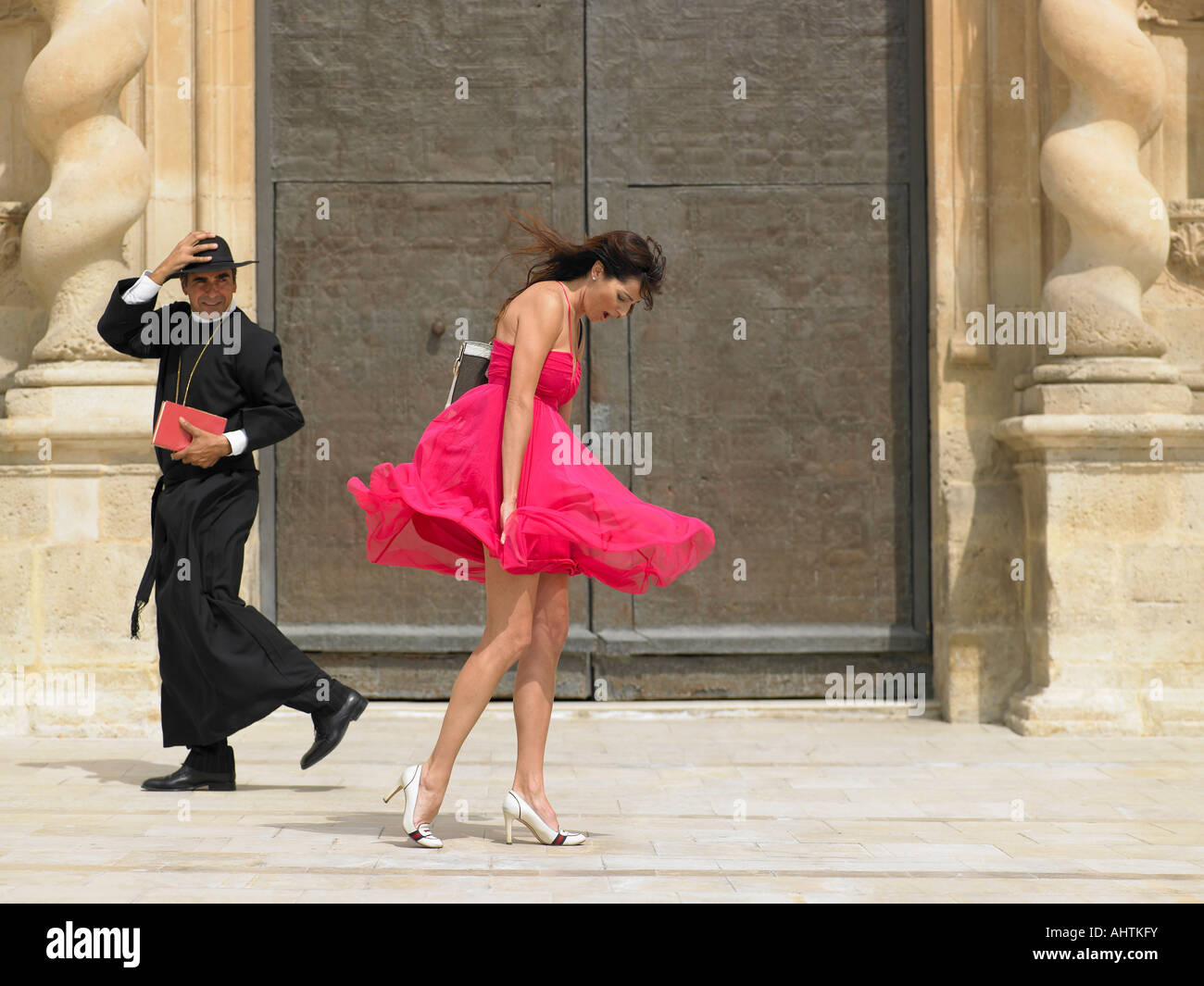 Sacerdote pasando mujer cuya falda está soplando en el viento, Alicante,  España Fotografía de stock - Alamy