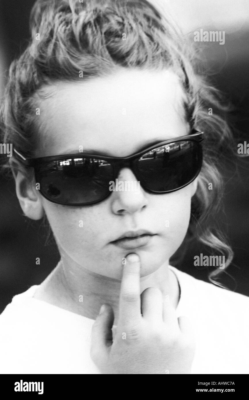 Niña de 8 a 10 años de edad llevaba gafas de sol adulto mirando  contemplativo con su dedo en su barbilla Fotografía de stock - Alamy