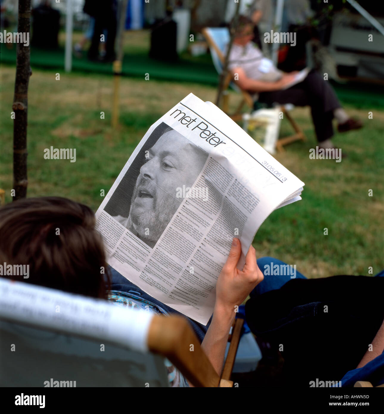 Una mujer leyendo sobre la reunión de los hermanos Christopher y Peter Hitchens en un artículo en el periódico The Guardian en hay Festival UK KATHY DEWITT Foto de stock