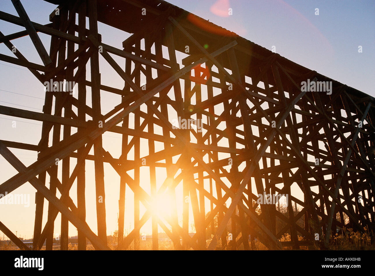 Rojo atardecer brillando a través de andamios de tren elevado puente Foto de stock