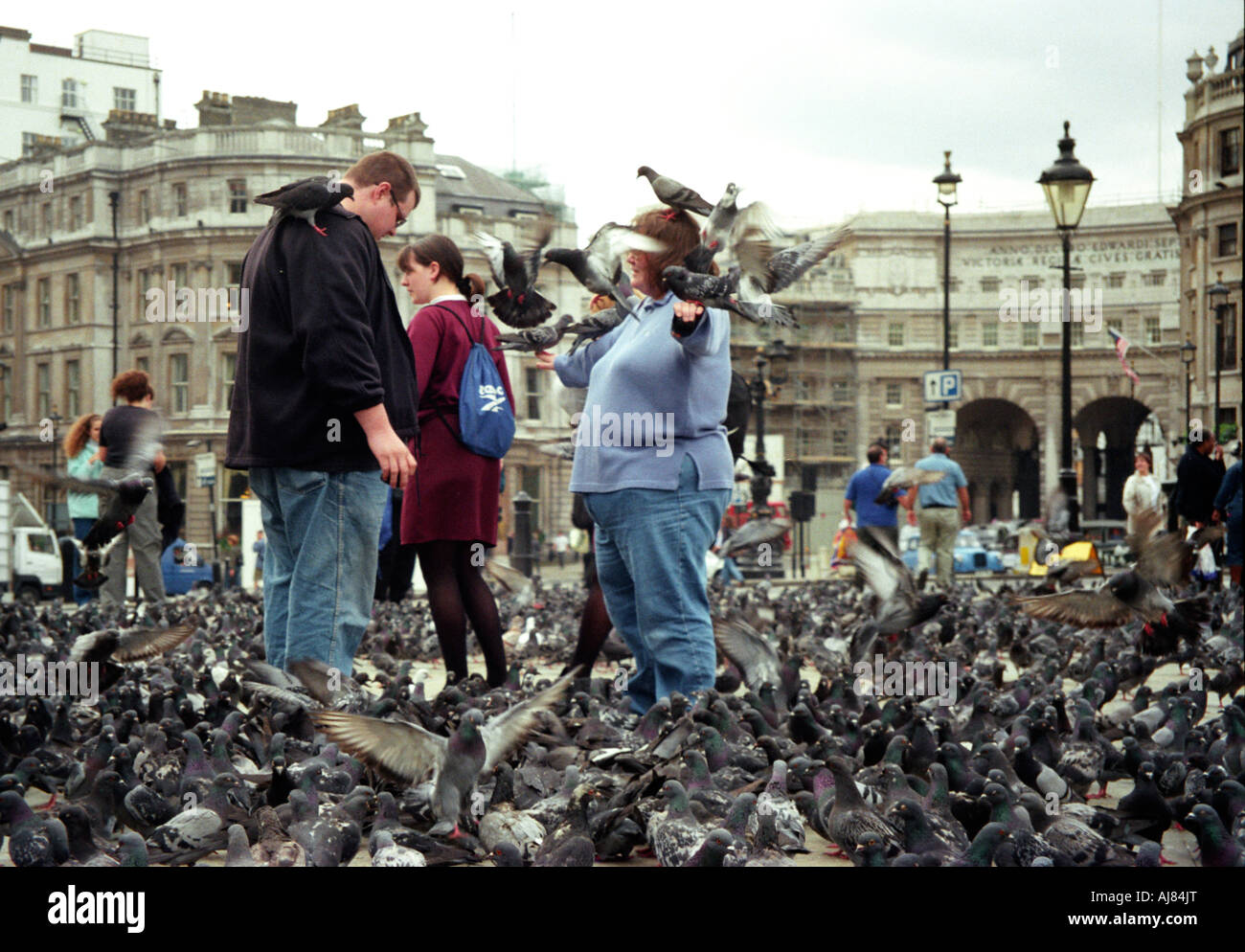 Una gran mujer permanece con aves encaramado sobre ella en Trafalgar Square en Londres, Reino Unido, Mayo 2000. Foto de stock