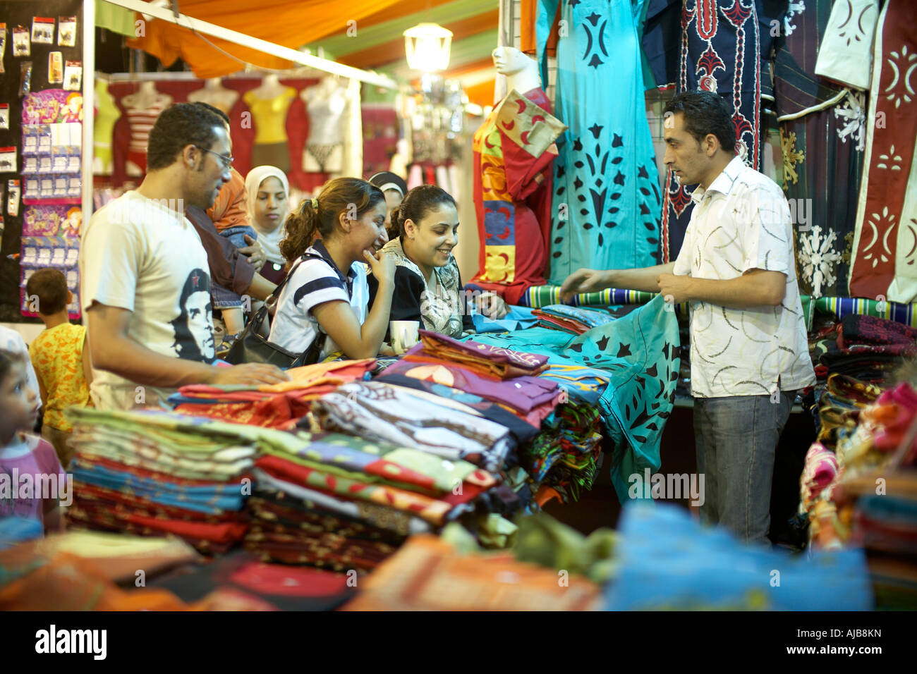 Las personas mirando tejidos o telas en exhibición en el mercado nocturno o souk cale en la tarde en la zona Mohandiseen El Cairo Egipto Foto de stock