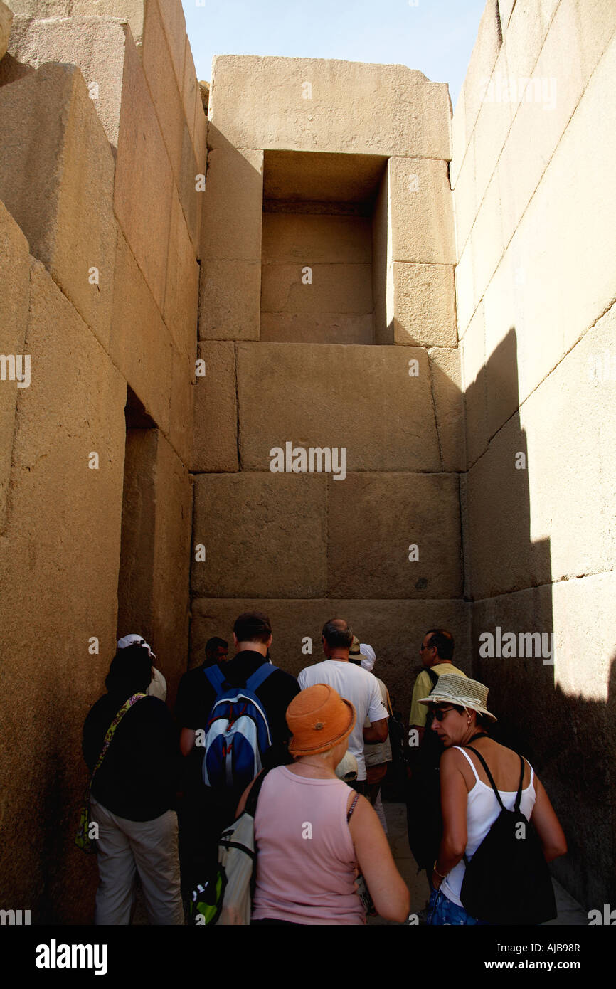 Los turistas en grupos turísticos caminando cerca apenas cortar bloques de piedra de Khafre s Templo del Valle Giza El Cairo Egipto África Foto de stock