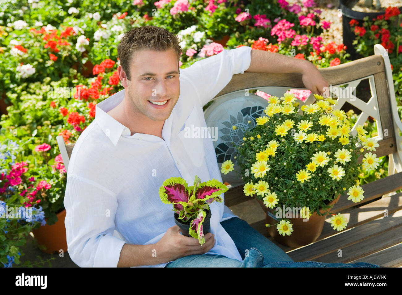 Joven descansando sobre banco en garden center (vertical), la vista (elevada) Foto de stock