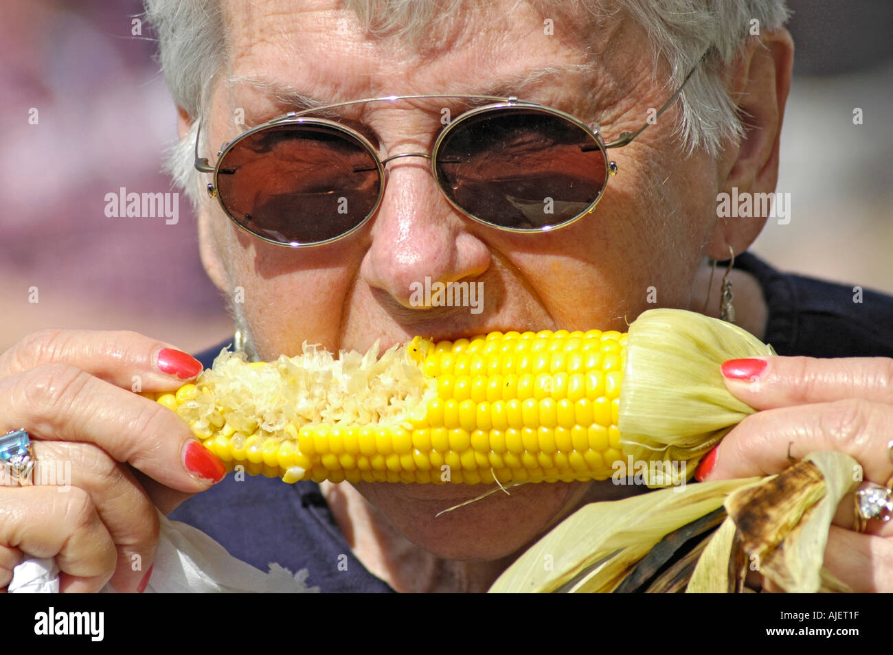 Gente real comiendo mazorcas de maíz ya sea al horno o a la parrilla o al  vapor de asados o en un palo por y con manos BBQ California EUA América  Fotografía