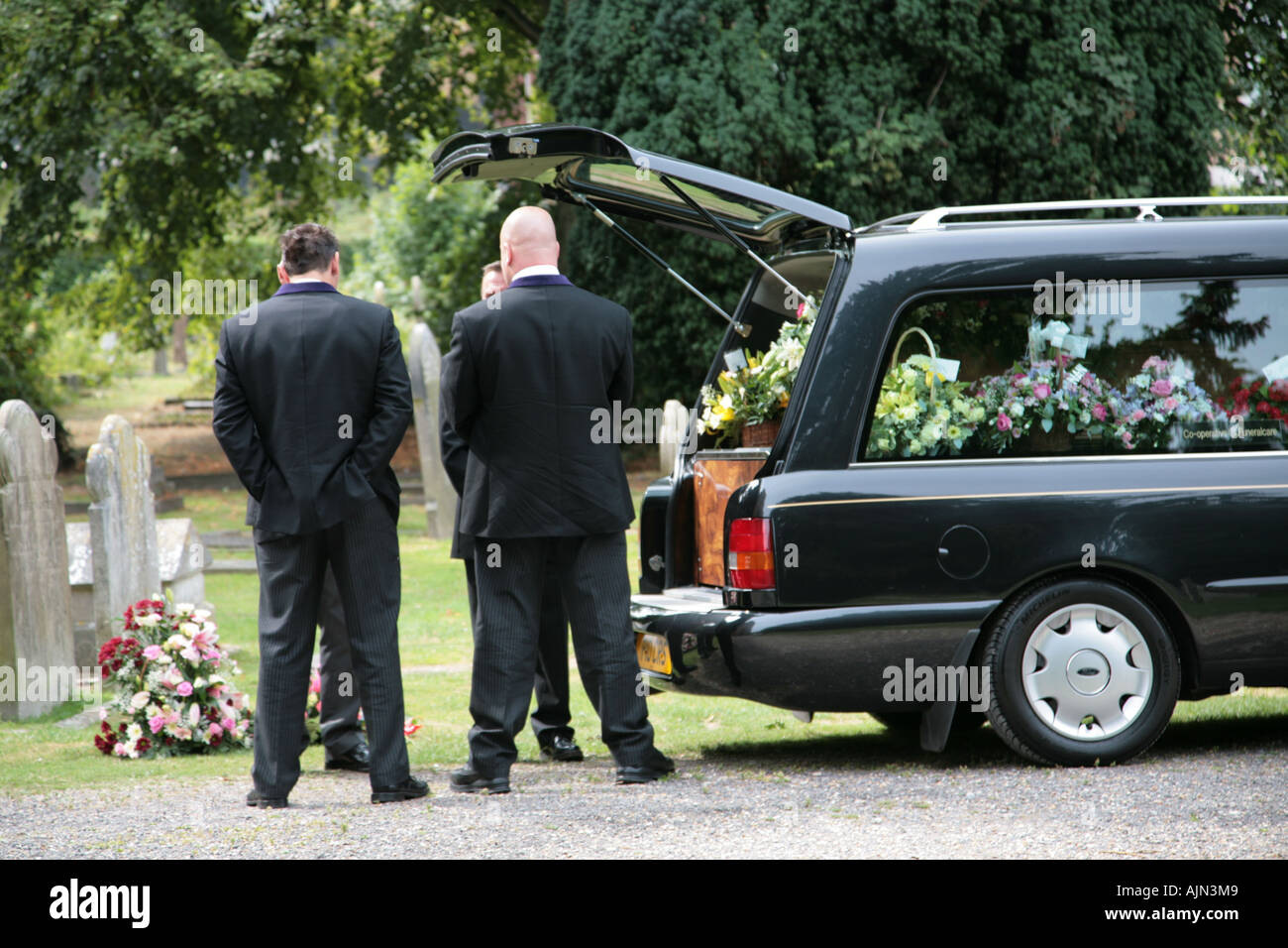 Directores de funerarias y portadores de Pall Preparando para quitar ataúd desde carroza Foto de stock