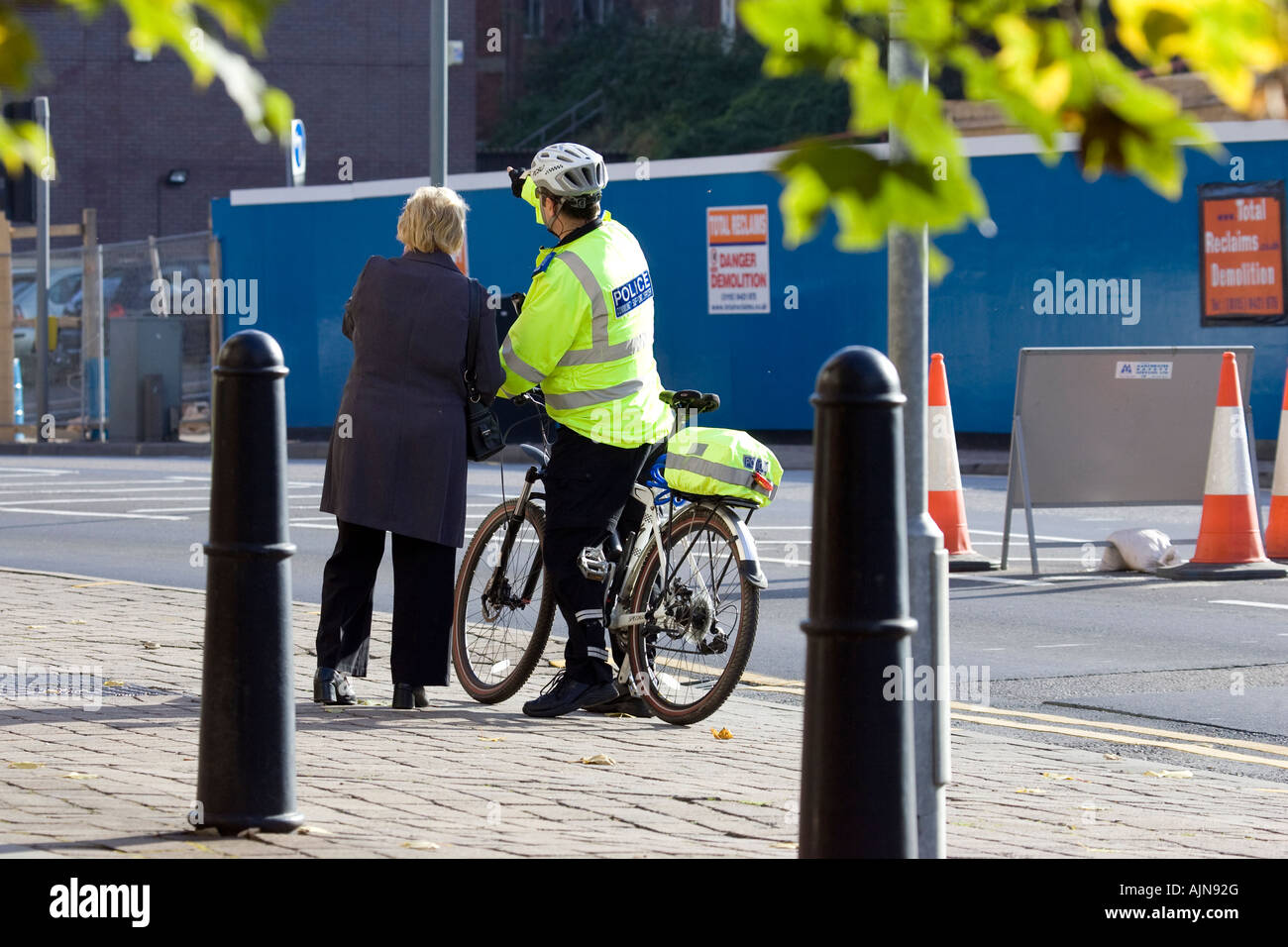 Oficial de policía comunitaria en una bicicleta dando instrucciones a un miembro del público. Foto de stock