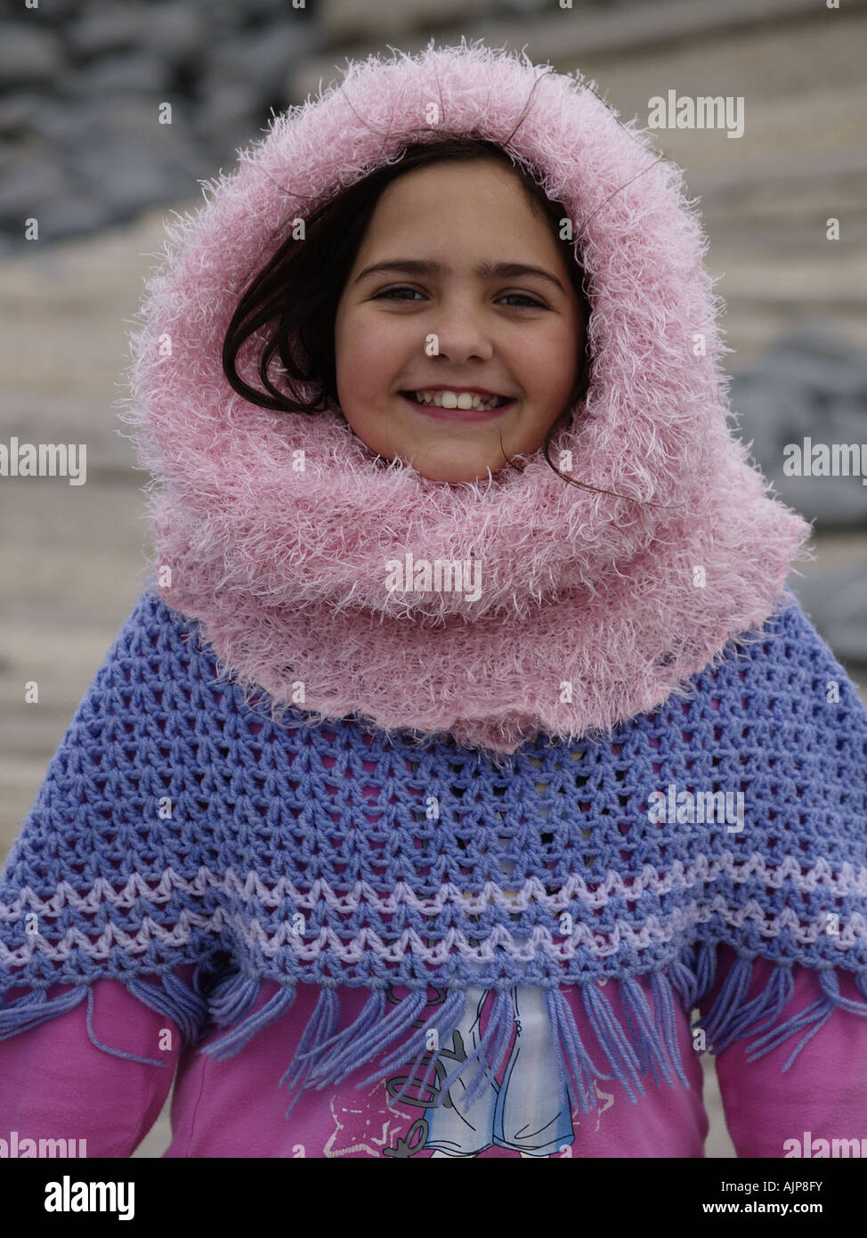 Una morena vestida de rosa bufanda tubo encima de su cabeza, woolly poncho y sonriente en la playa Fotografía de - Alamy