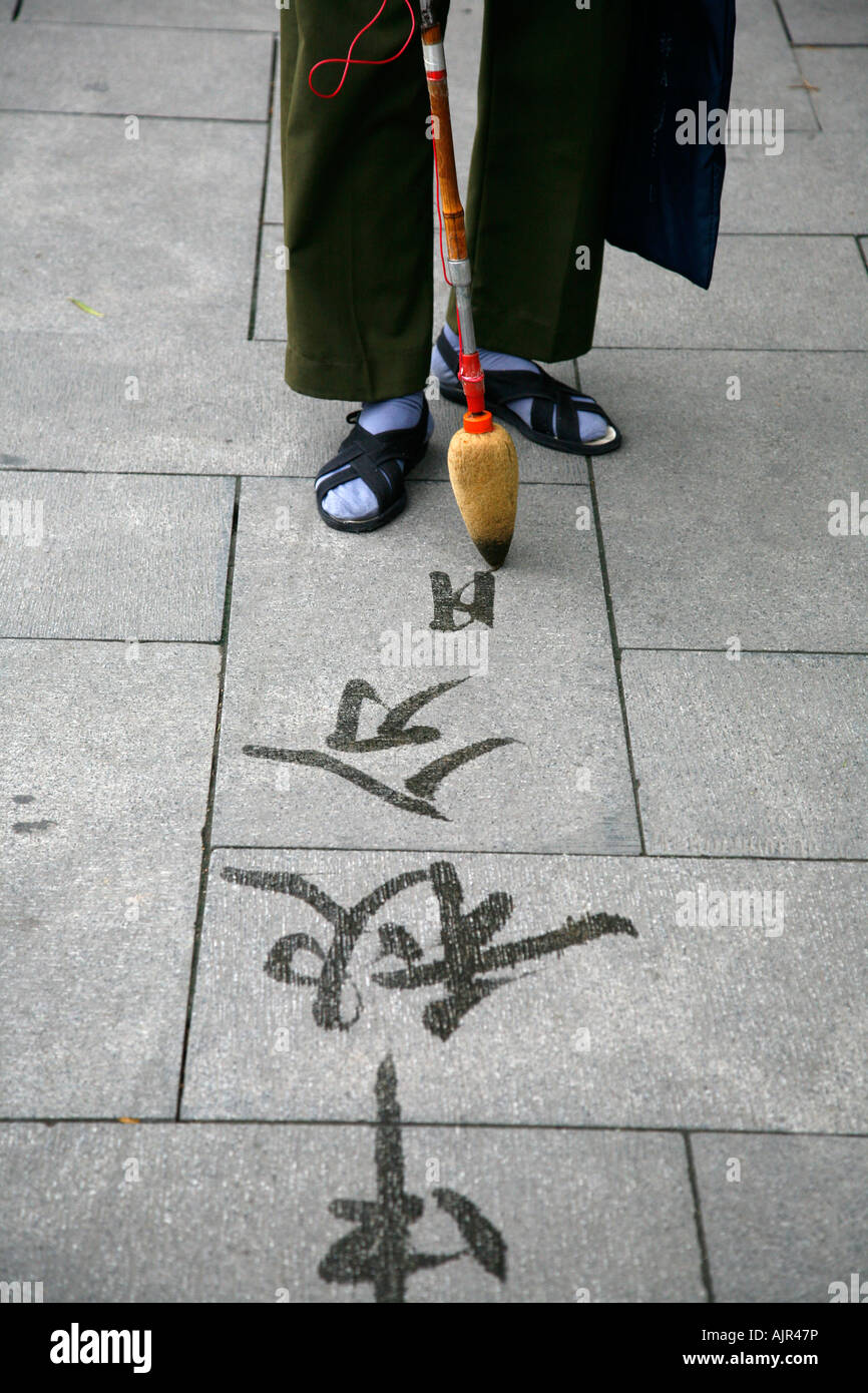 Hombre escribir caligrafía en el suelo con agua cepillo en el parque Beihai Beijing China Foto de stock