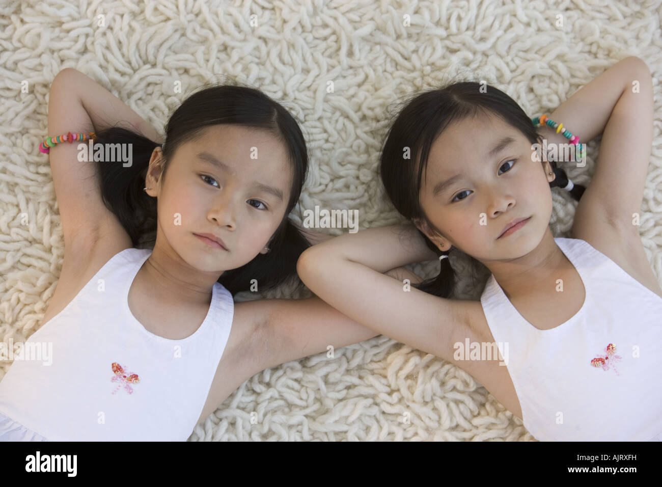 Retrato de hermanas gemelas acostado sobre una alfombra mirando hacia  arriba Fotografía de stock - Alamy