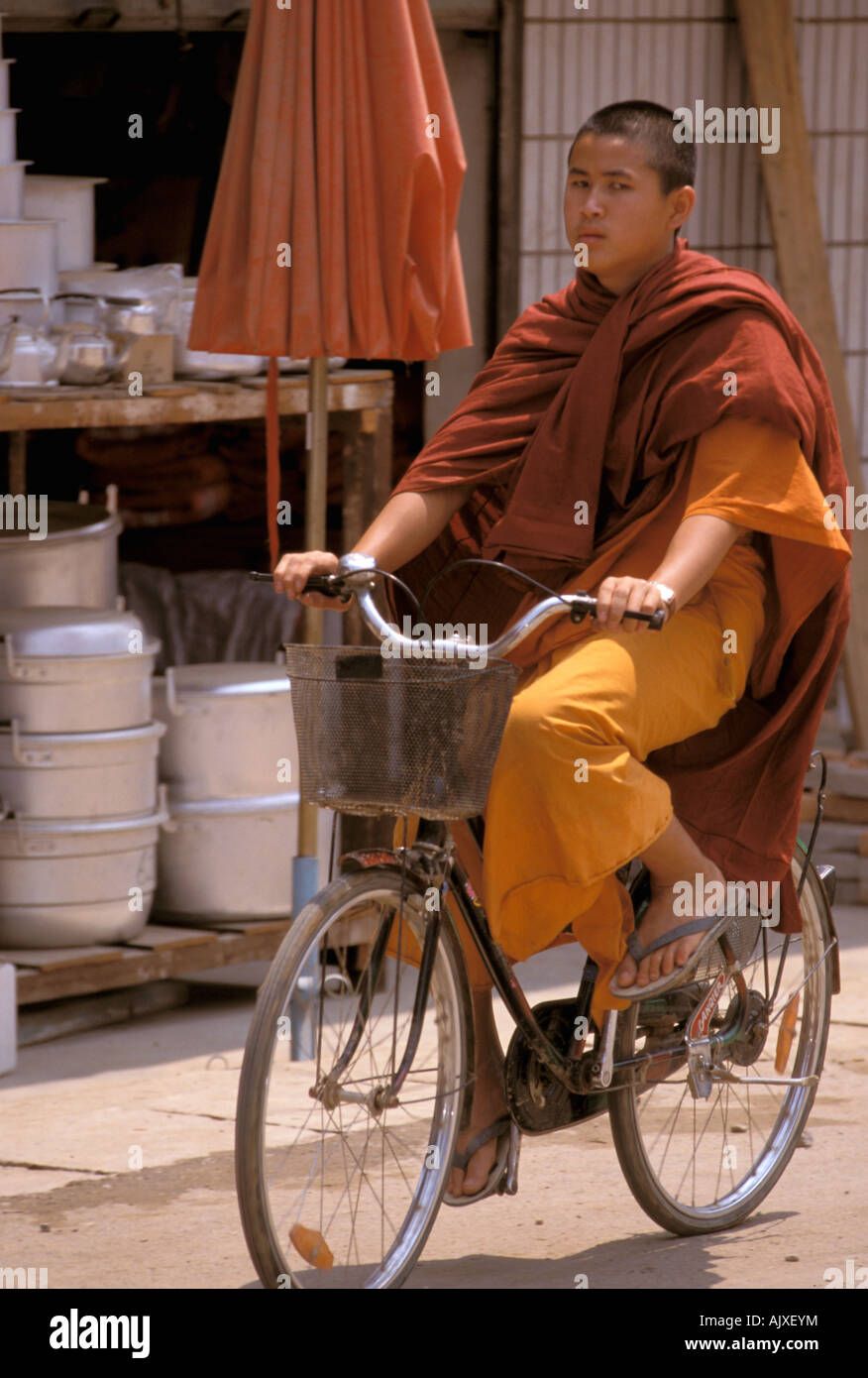 En Asia, China, en la provincia de Yunnan, Xishaungbanna, Mong Village.  Naranja monje togada paseos en bicicleta por el pueblo Fotografía de stock  - Alamy