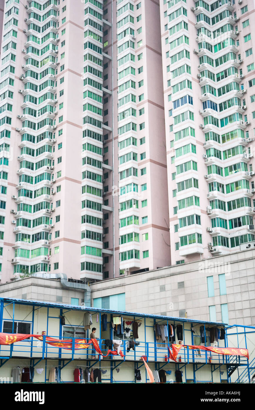 Persona colgar la ropa a secar en la terraza del edificio, bajo imponentes rascacielos en segundo plano. Foto de stock
