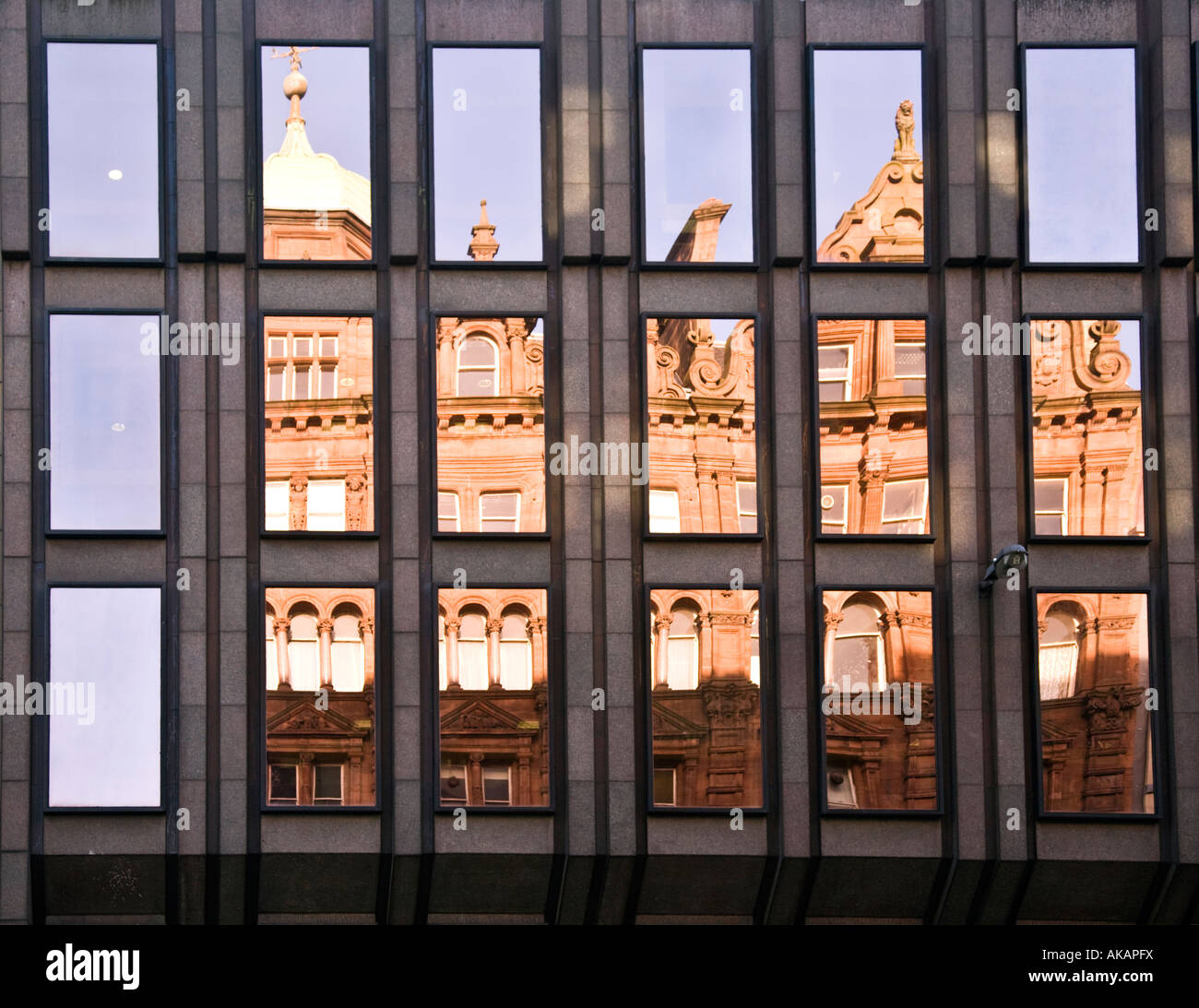 Un viejo edificio Victoriano reflejado en las ventanas de un moderno bloque de oficinas en Glasgow, Escocia. Foto de stock