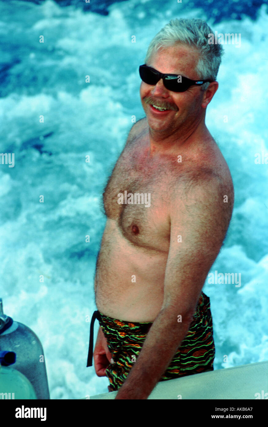 Un hombre canoso chested desnudo vistiendo shorts disfruta contemplando el  espumoso de las olas del mar Fotografía de stock - Alamy