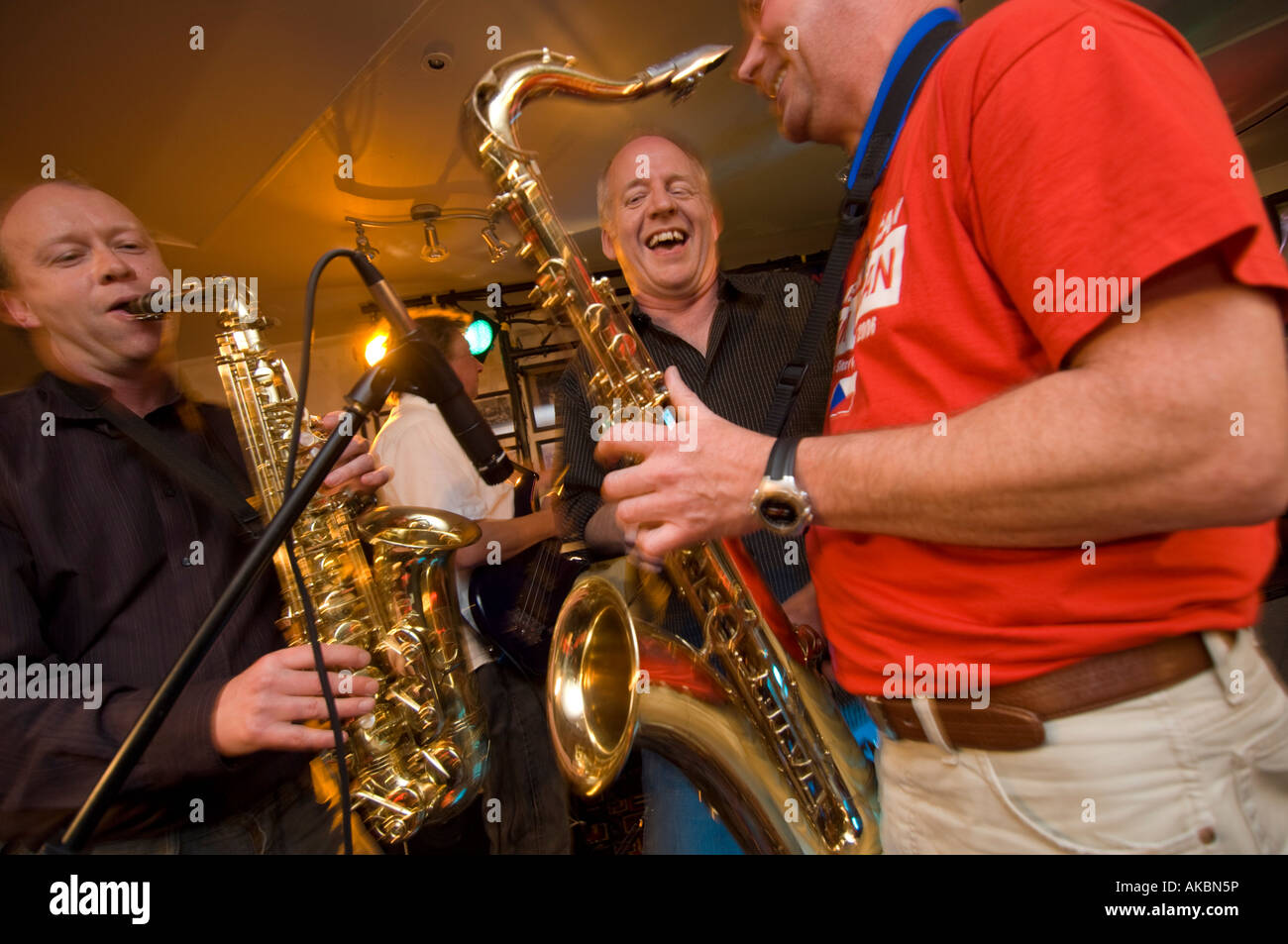 Tres feliz sonriendo riendo masculino músicos tocando música de jazz en un club nocturno Foto de stock