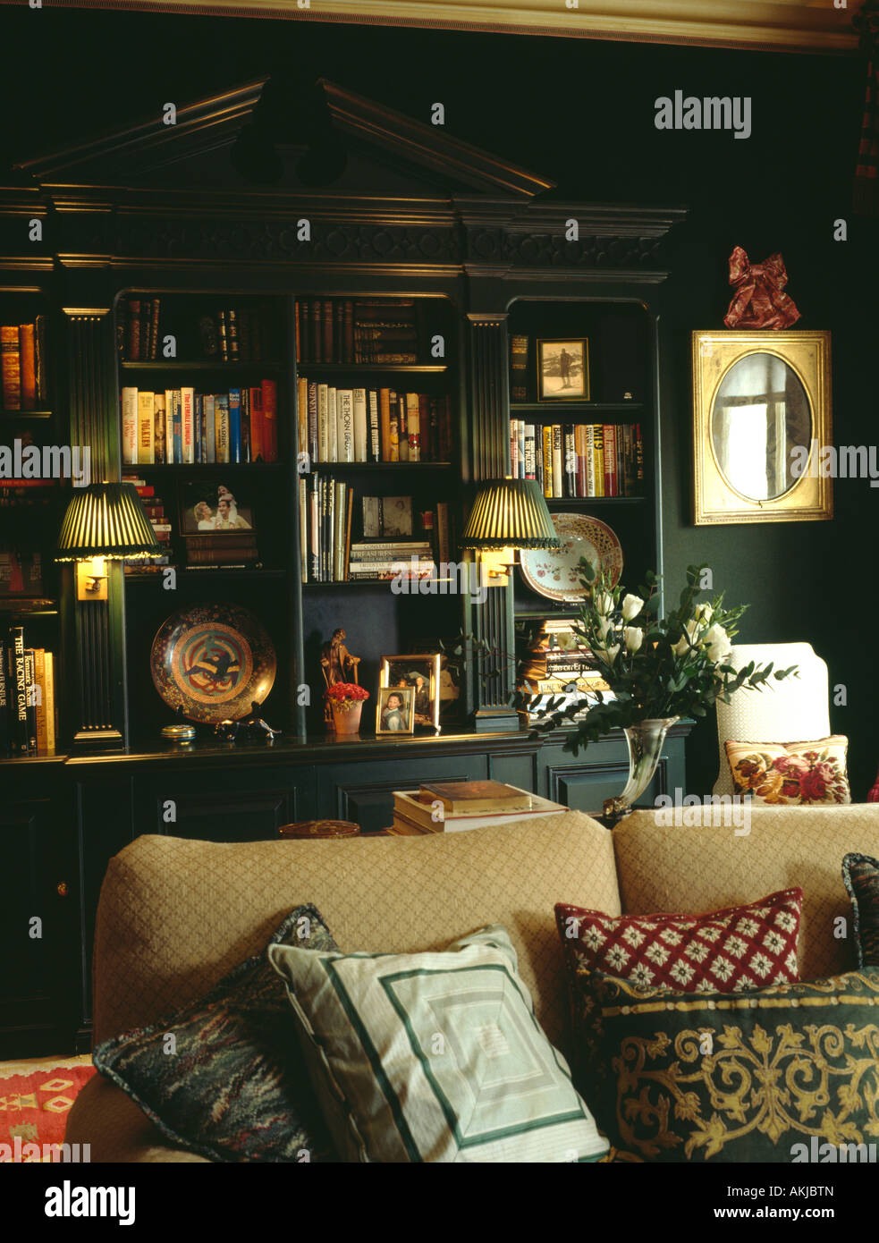 Lámparas encendidas en estanterías montadas en verde oscuro salón con  cojines apilados en crema sofá Fotografía de stock - Alamy