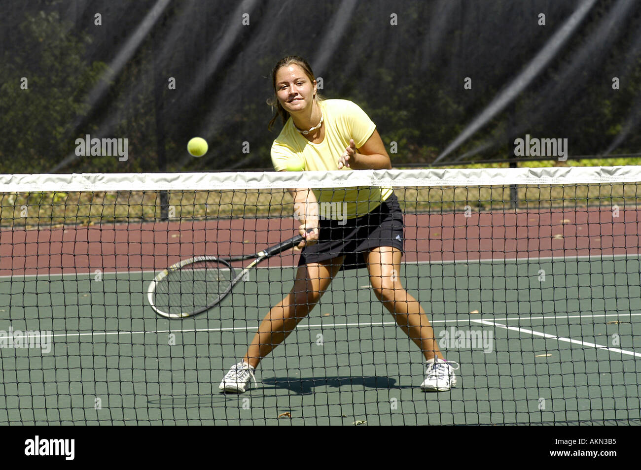 Jugador de tenis femenino en un colegio cumplir en la red golpeando la bola Foto de stock