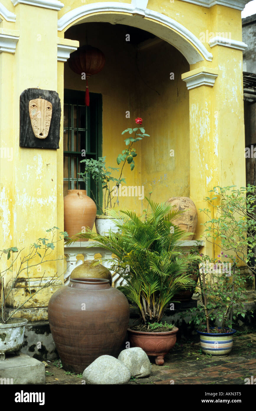 Amarillo columnata arqueada, macetas y plantas en ladrillo patio adoquinado de casa, Nguyen Thi Minh Khai St, Hoi An, Vietnam Foto de stock