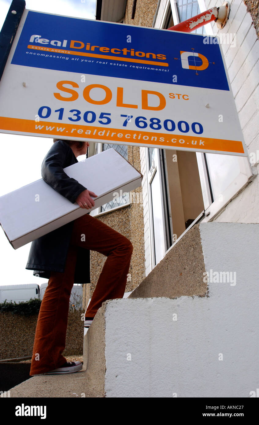 Una mujer toma una caja en su casa nueva Foto de stock