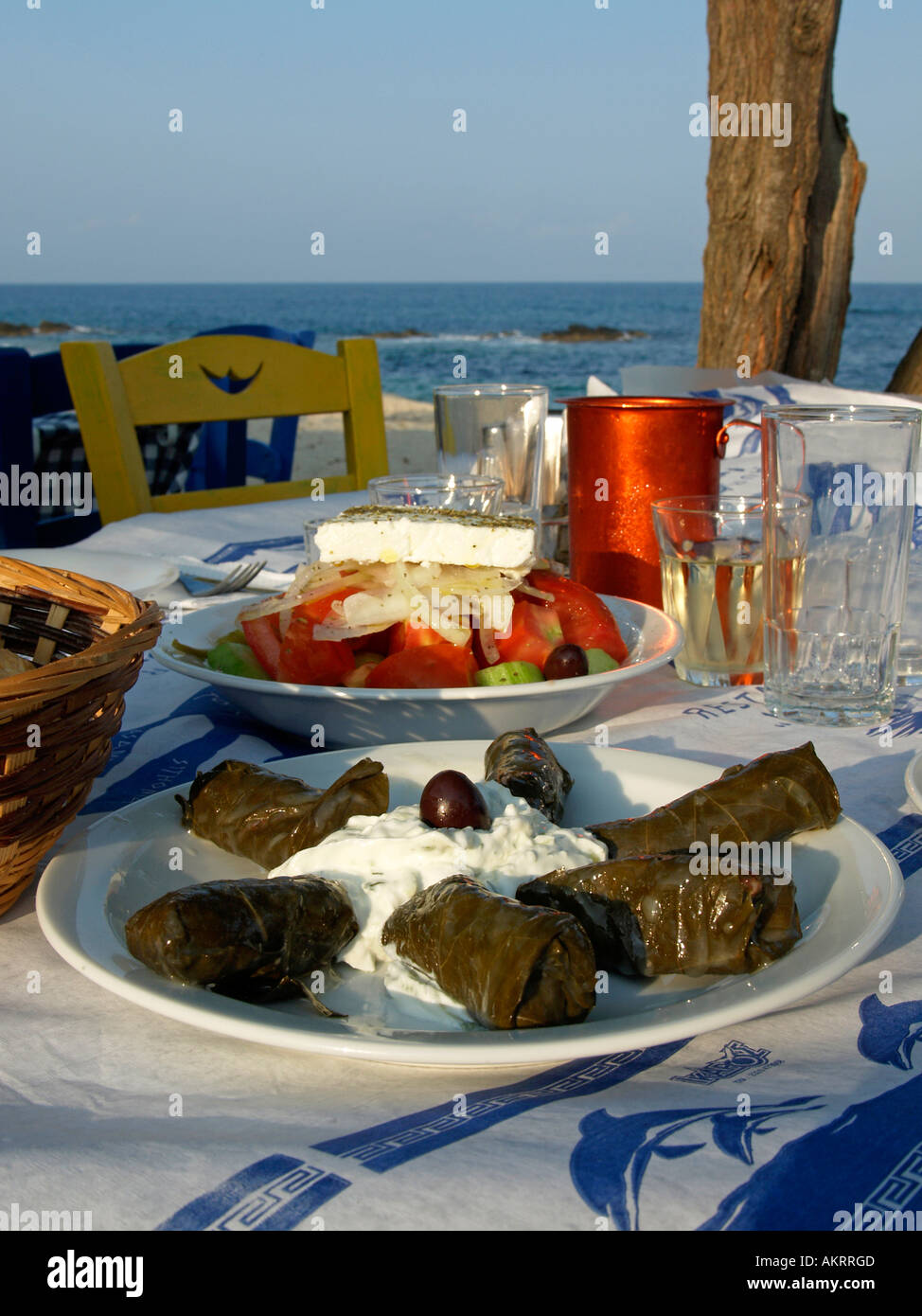 Comida griega típica Tsatsiki Tsaziki Tzaziki Doladakia hojas rellenas de ensalada griega vid vino en una mesa en la playa de Sarti Foto de stock