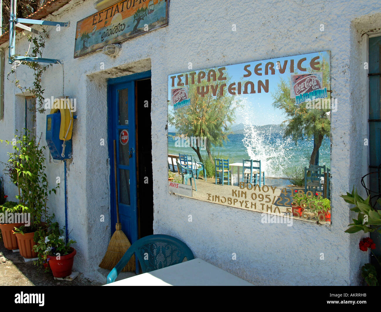 Bar restaurante Kafenion griego con un espejo en la pared, reflejando el punto de vista del mar y de las olas salpicando contra la pared Foto de stock