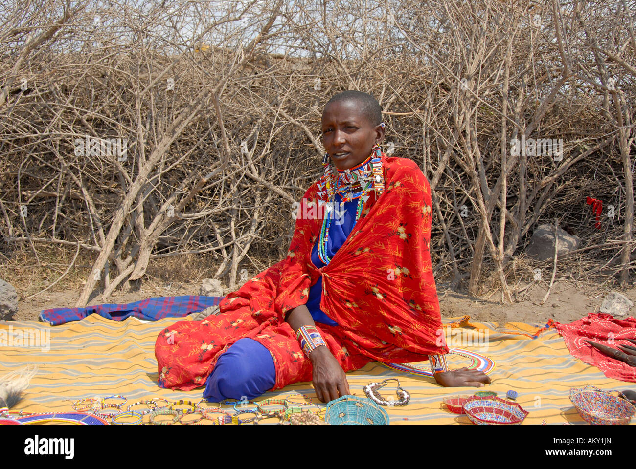 Mujer masai vestido con un capote rojo vende souvenirs en el kraal Parque Nacional Amboseli Kenia Foto de stock