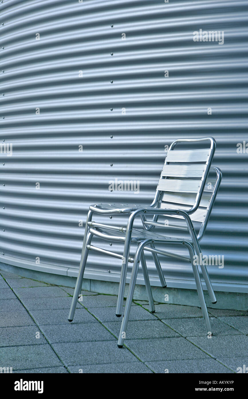 Dos sillas de aluminio delante de una pared de hierro ondulado Foto de stock
