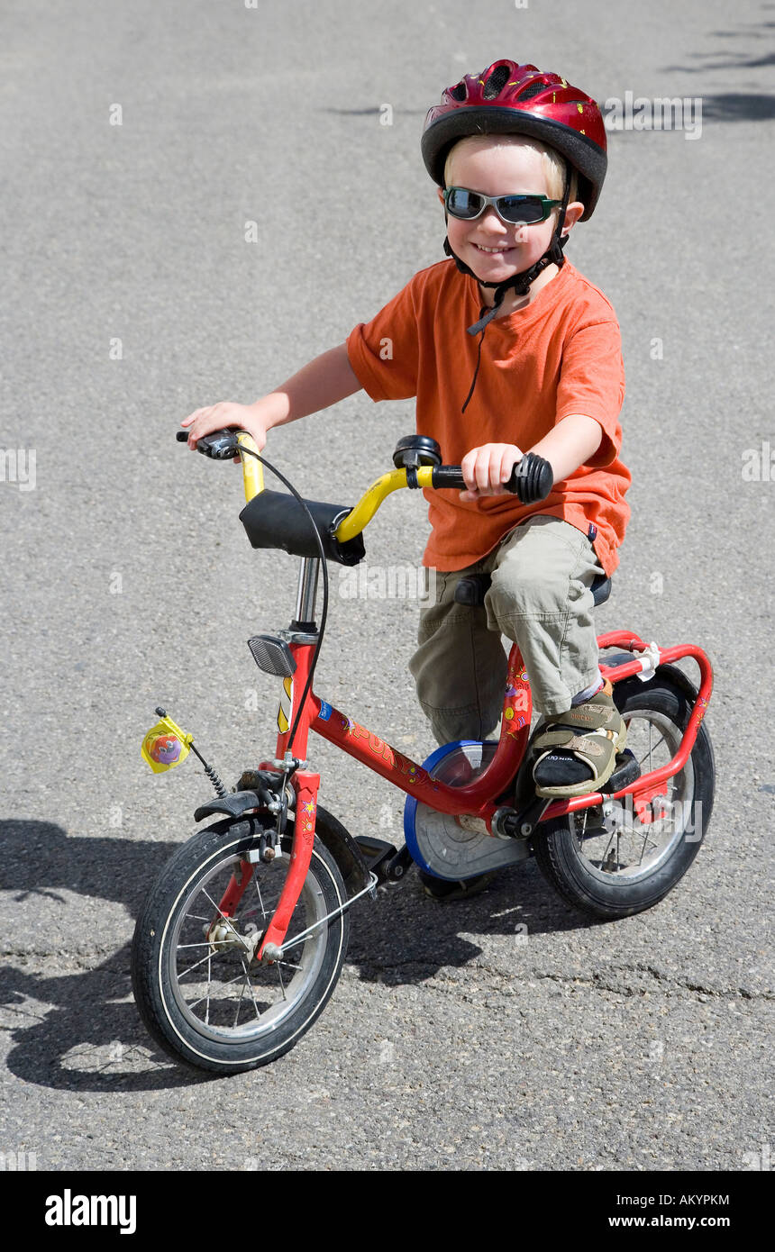 Un niño de tres años, con un casco de bicicleta y gafas de sol en