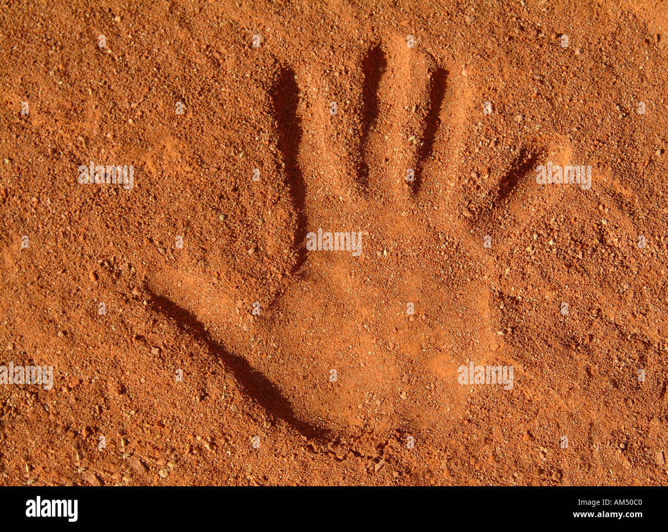 Impresión de mano humana en arena rojiza Foto de stock