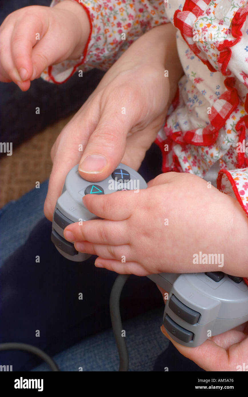 Cerca de las niñas y las madres manos usando el controlador Sony Playstation Foto de stock