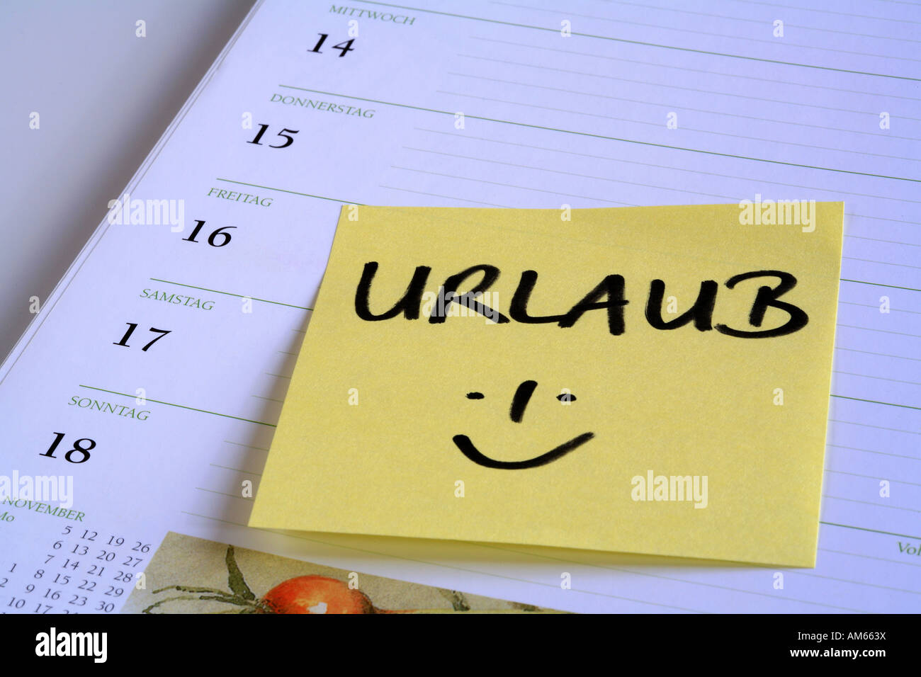 Nota de aviso amarillo "Urlaub' (vacaciones) en la página de un calendario Foto de stock