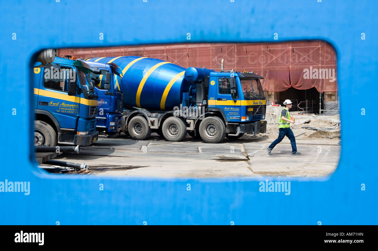 Ver a través de una valla sitio azul: azul mezcladoras de cemento en construcción Foto de stock