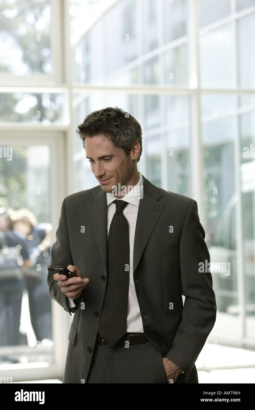 Hombre de negocios con un teléfono móvil en el vestíbulo Foto de stock