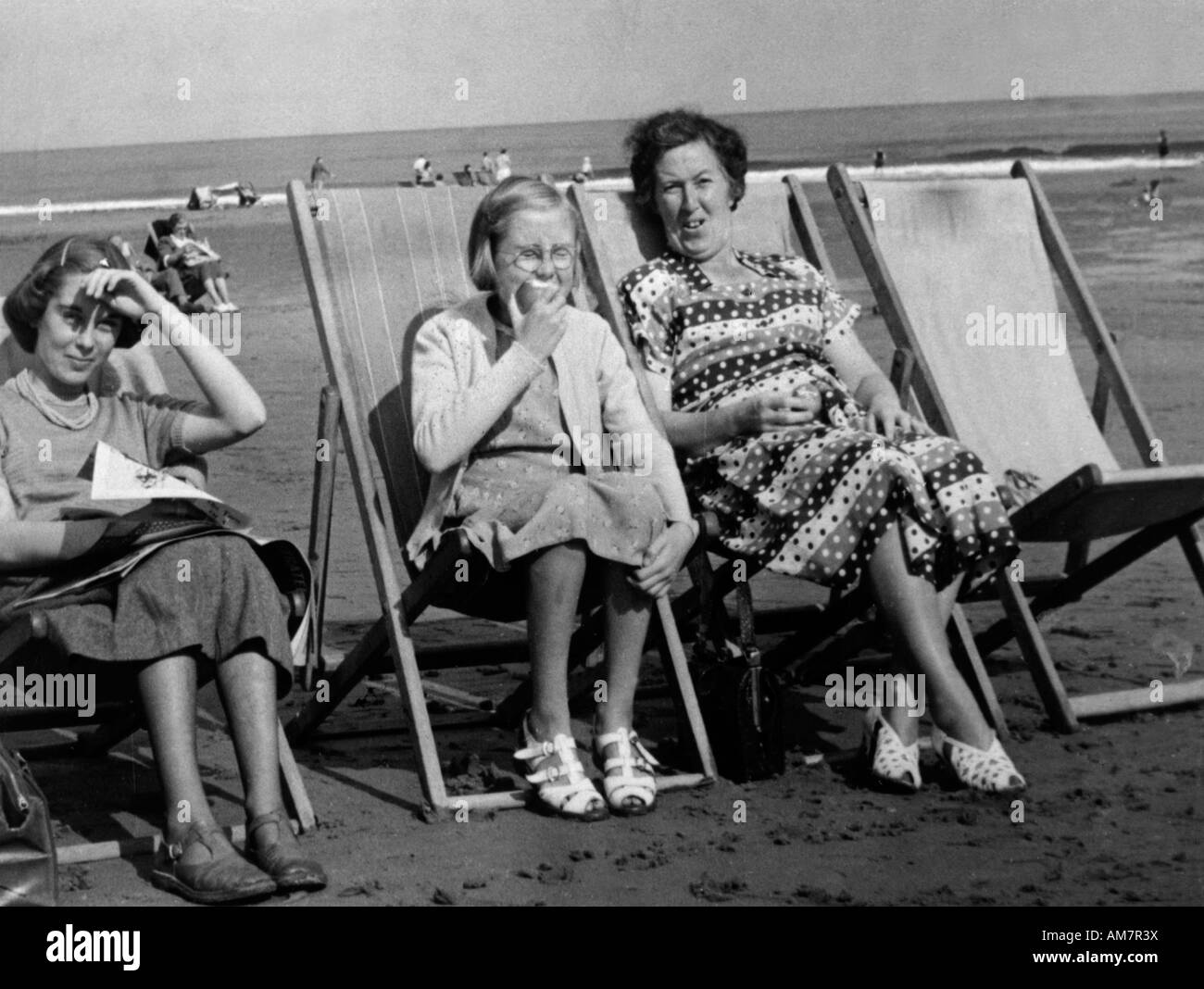 Antigua fotografía instantánea de la familia vintage de la madre y sus dos  hijas, sentados en reposeras en la playa Fotografía de stock - Alamy