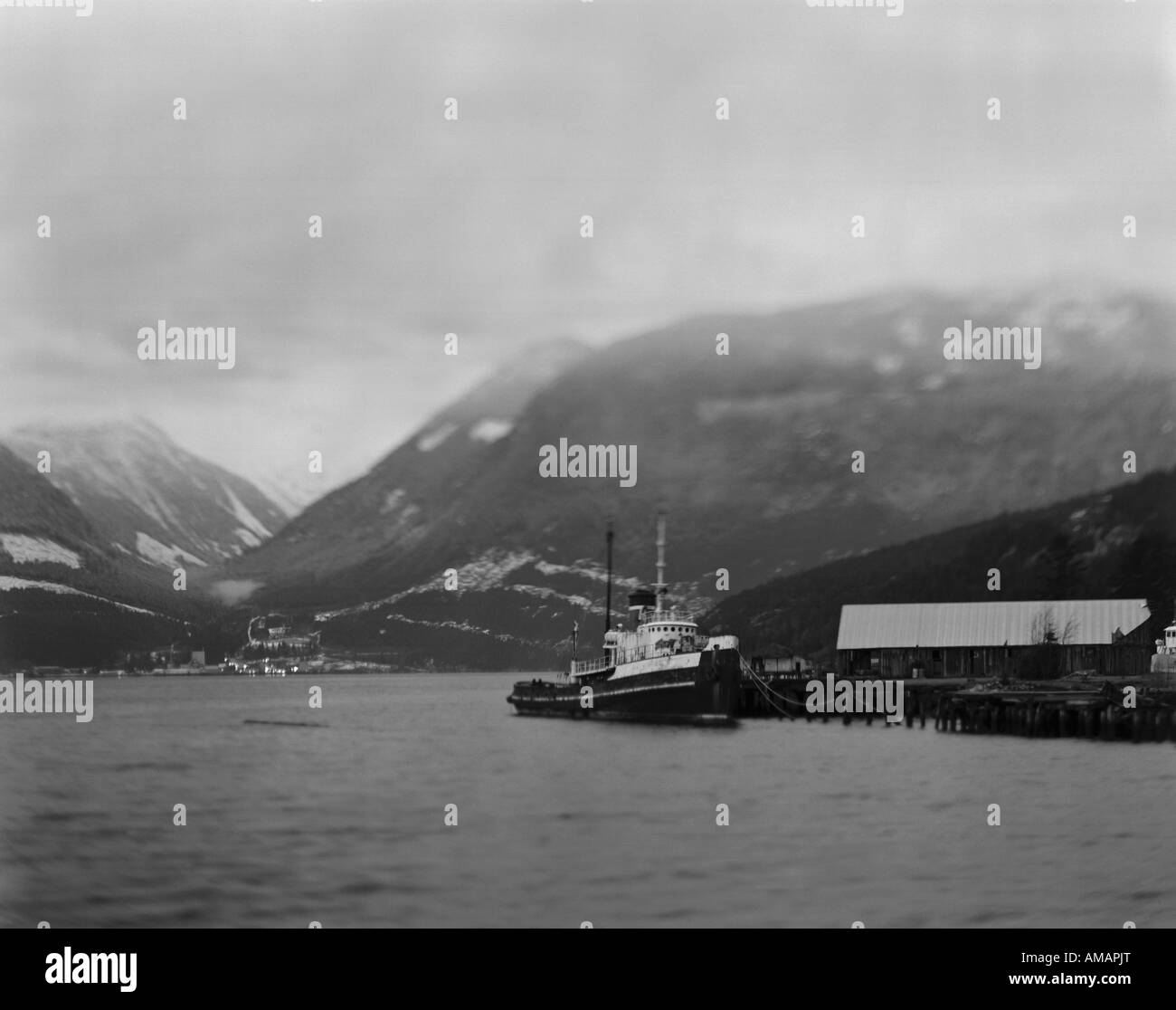 Un remolcador en un puerto rodeado por montañas Foto de stock