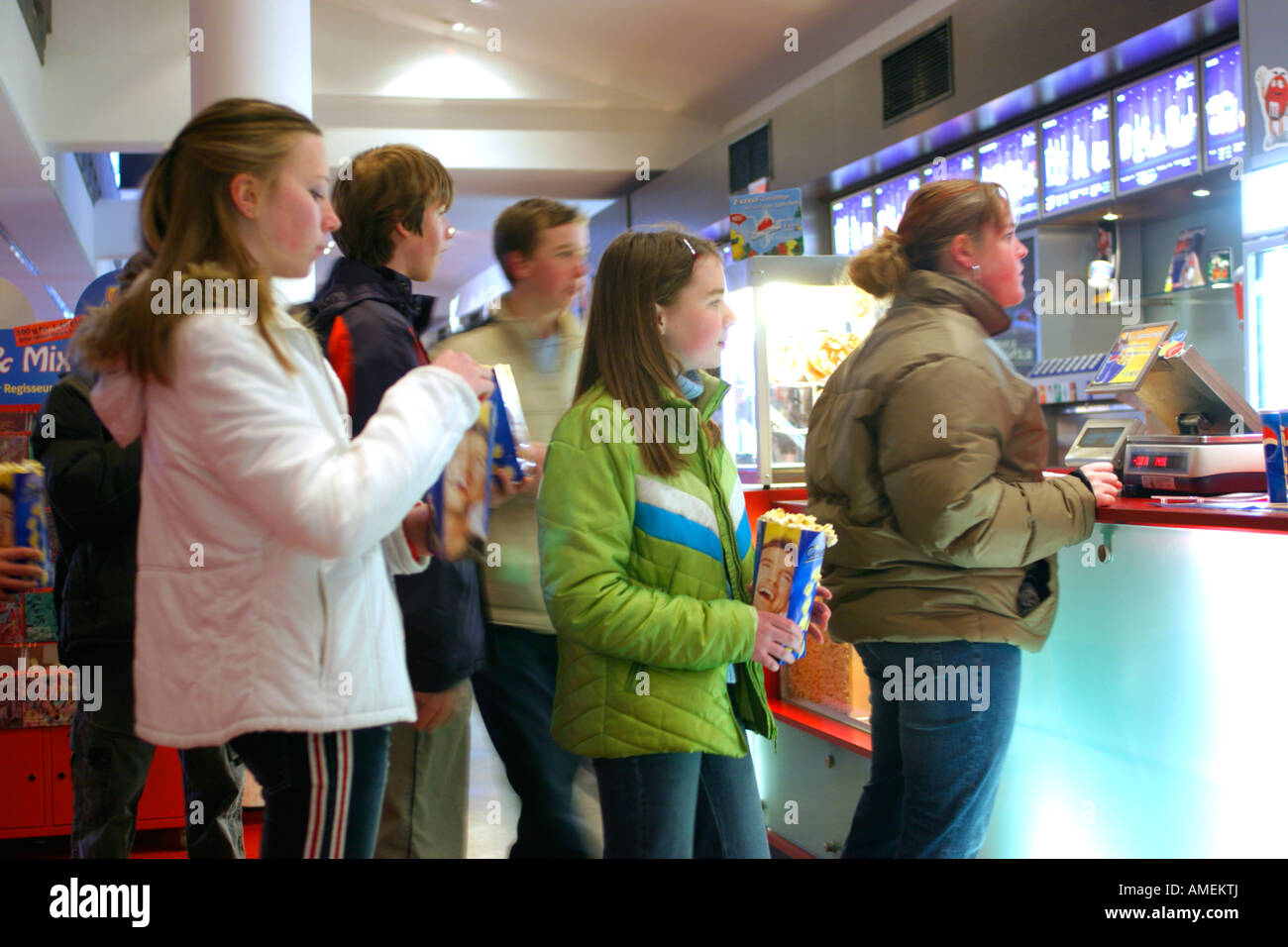 Los adolescentes dulces haciendo cola para entrar en un cine antes de la película comienza Foto de stock
