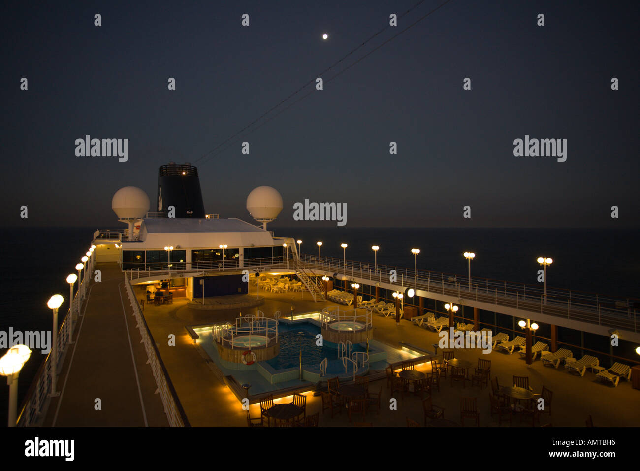 Mirando hacia la popa en la plataforma superior de la camisa de pasajeros  de cruceros con luna llena sobre buque mientras que en el mar por la noche  en el Océano Pacífico