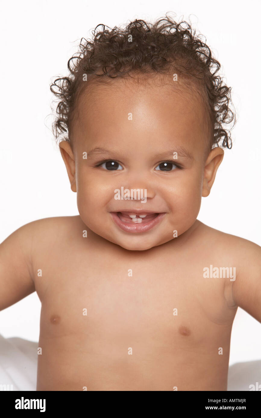 Un bebé de pelo rizado se asienta sobre un fondo blanco y sonrisas  Fotografía de stock - Alamy