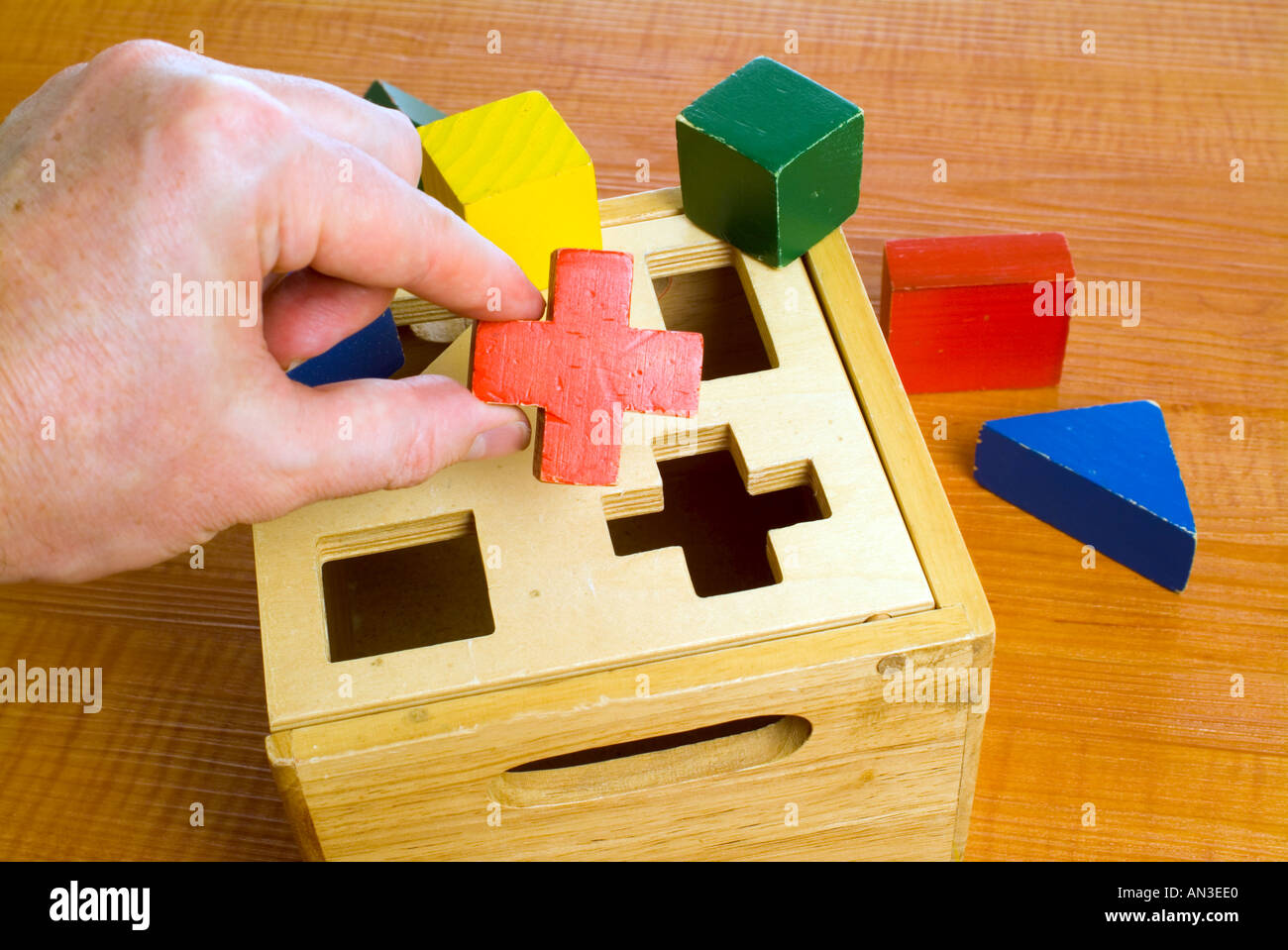 Poniendo la mano piezas de puzzle de madera Fotografía de stock - Alamy