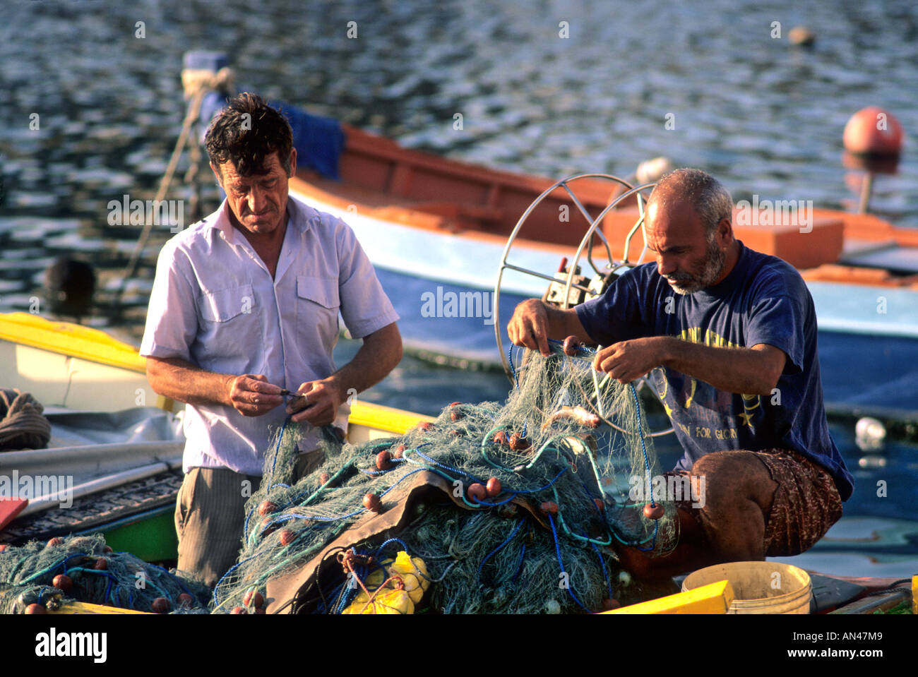 Dos pescadores, Malta, Europa - remendando redes en el puerto Foto de stock