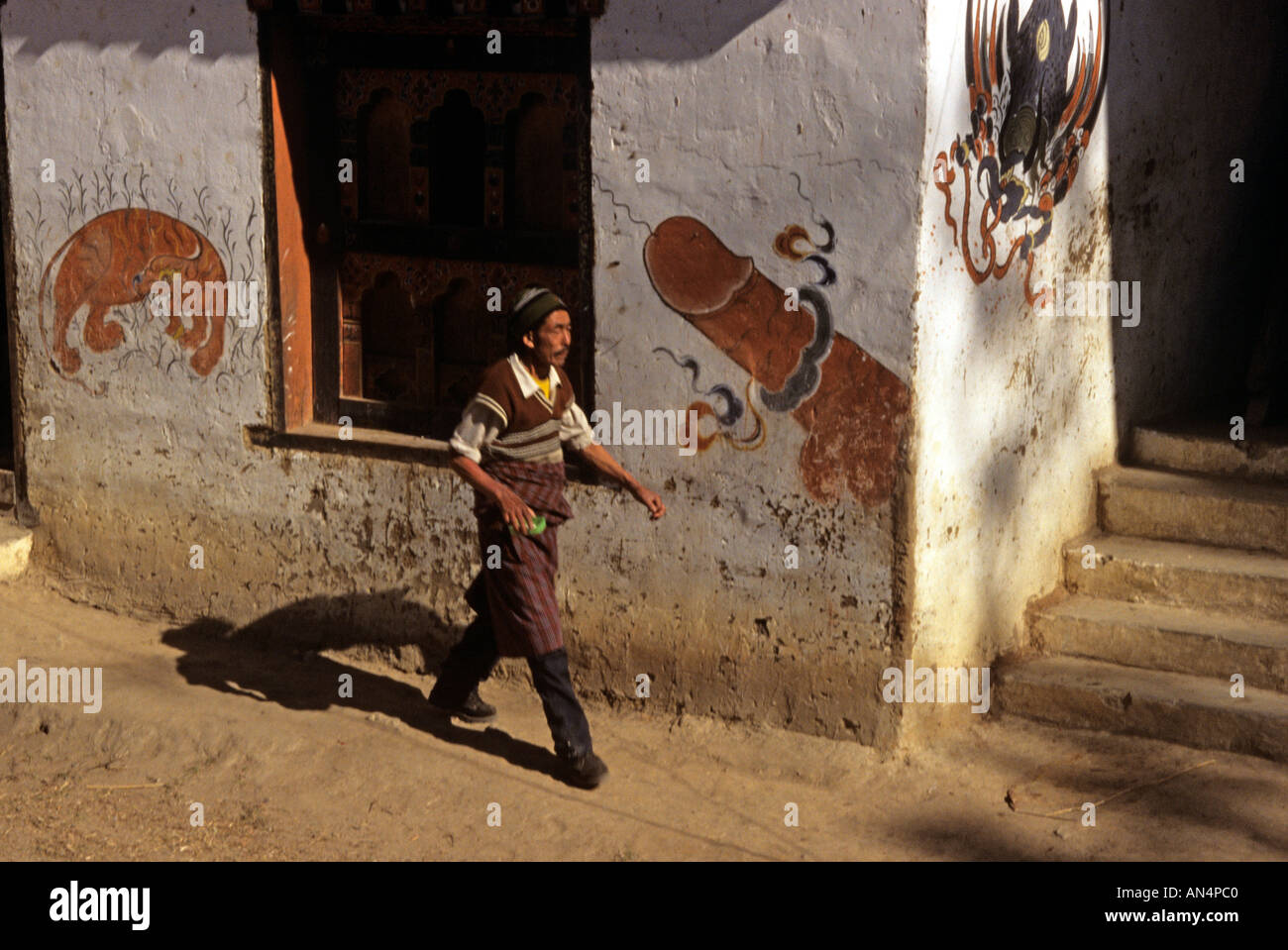 Un hombre camina pasa el símbolo de la fertilidad Bhután Foto de stock