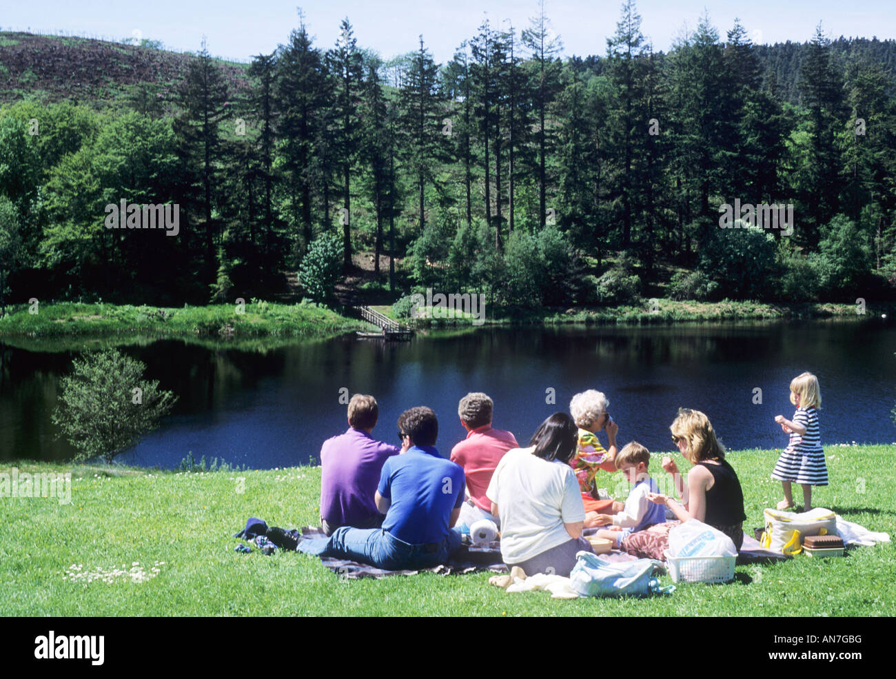 Picnic familiar Cragside Country Park Northumberland Inglaterra padres niños comiendo afuera campo lago Foto de stock