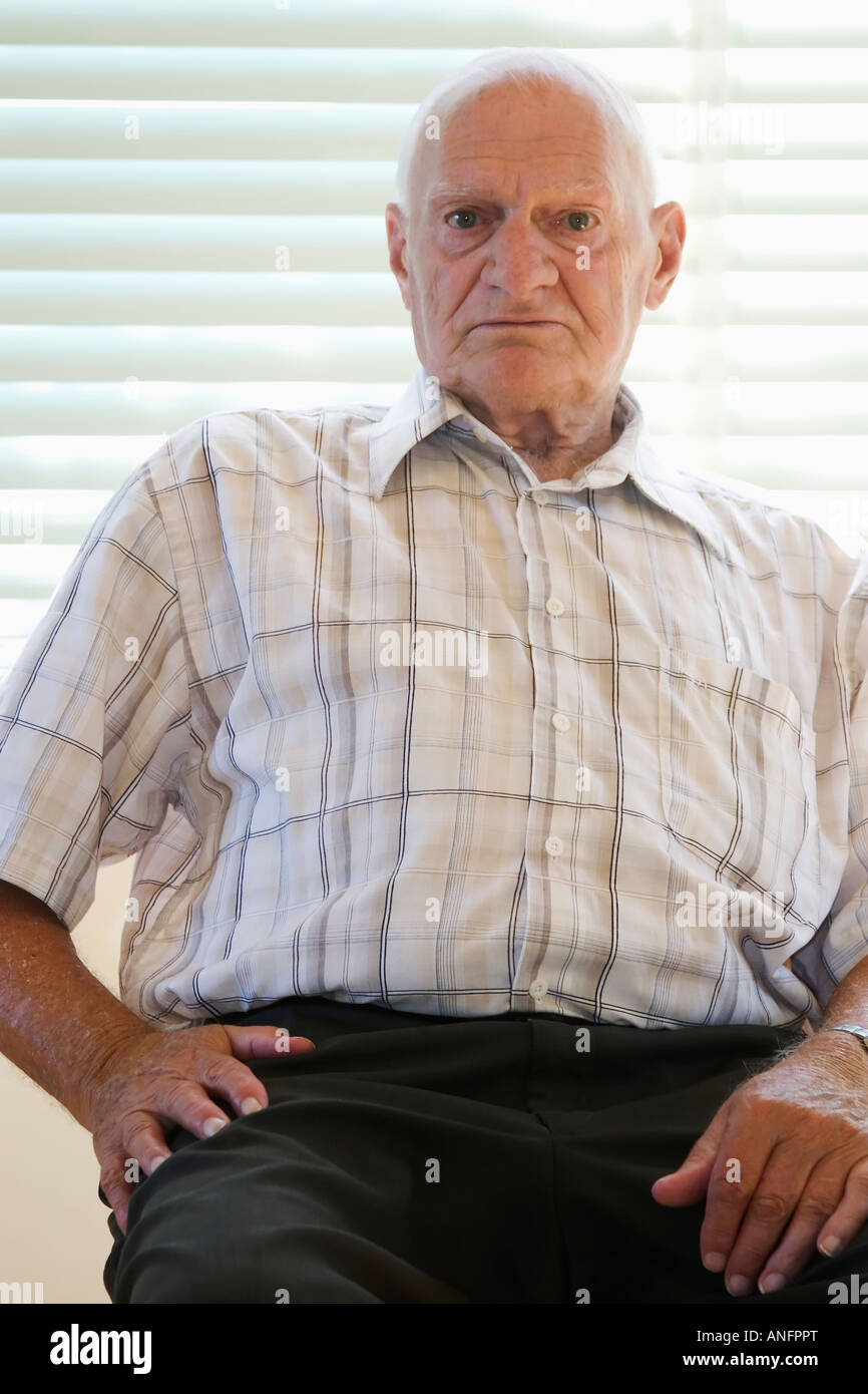Senior Citizen (70-80 años) sentado en una silla en casa vacía, Canadá. Foto de stock