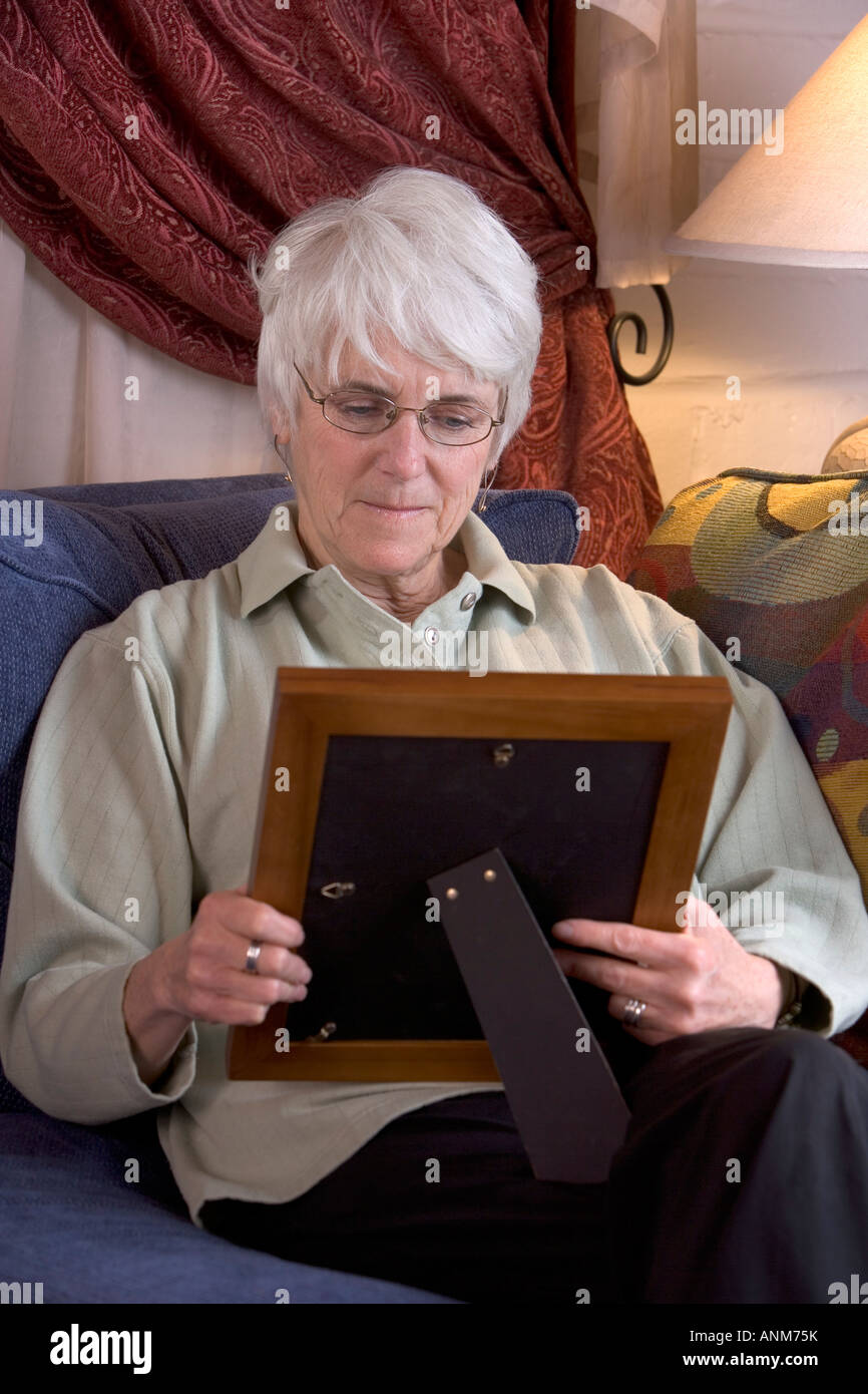 Senior mujer sostiene la fotografía de un ser querido. Foto de stock