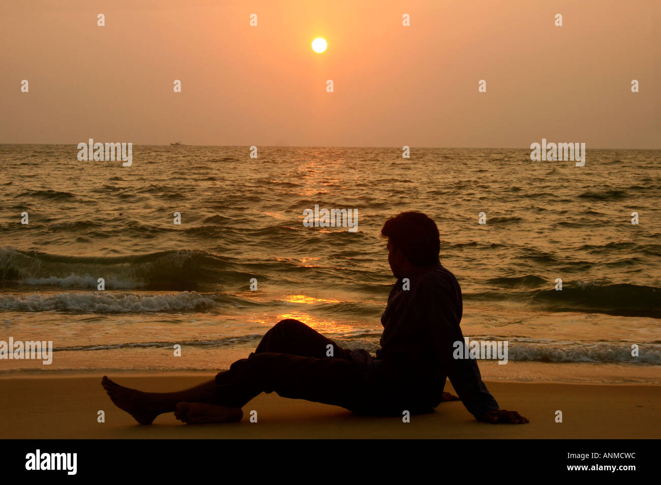 Hombre sentado en una playa viendo atardecer Alapuzha Kerala Foto de stock