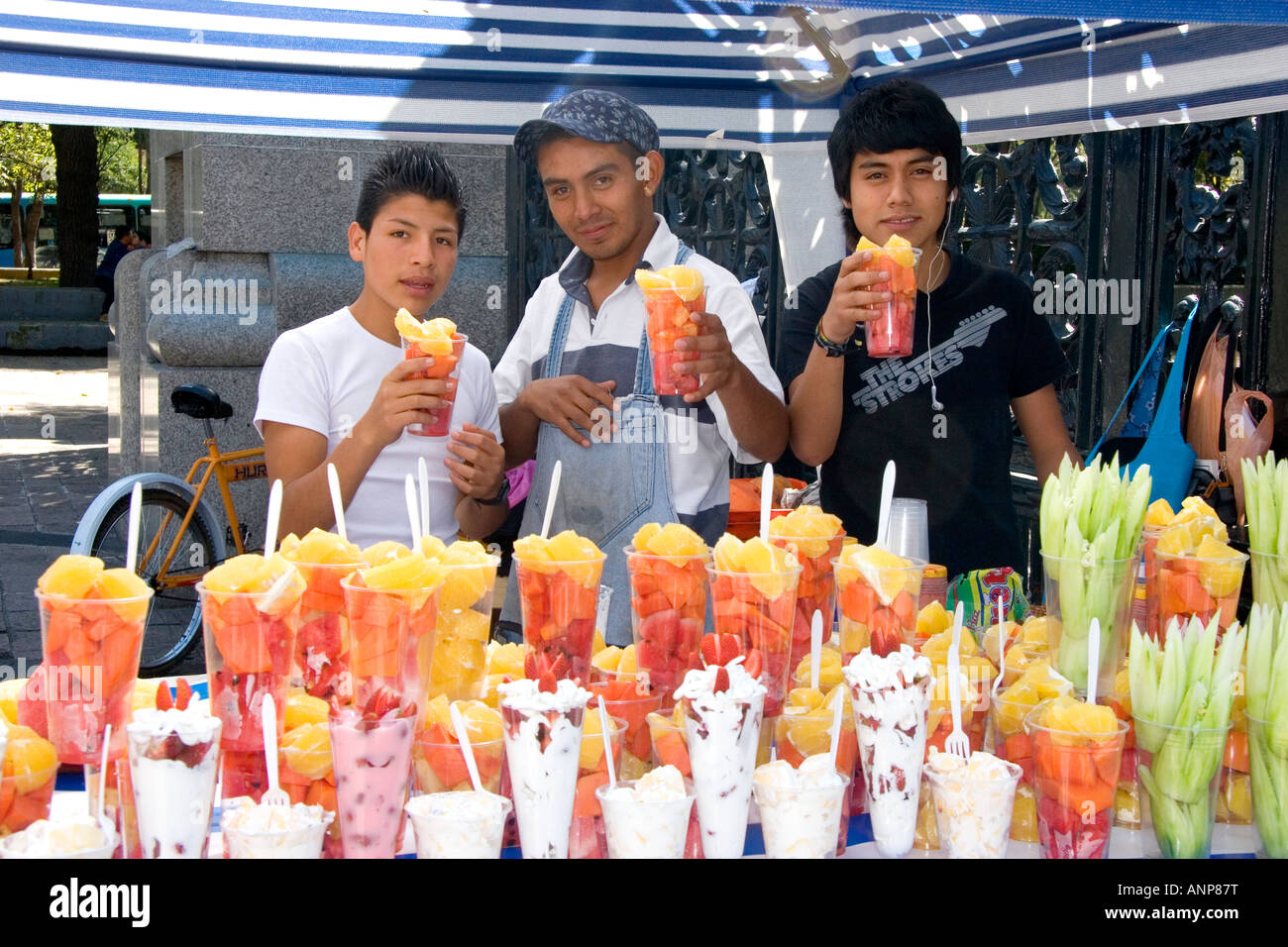 Joven mexicano los vendedores callejeros que venden tazas de fruta