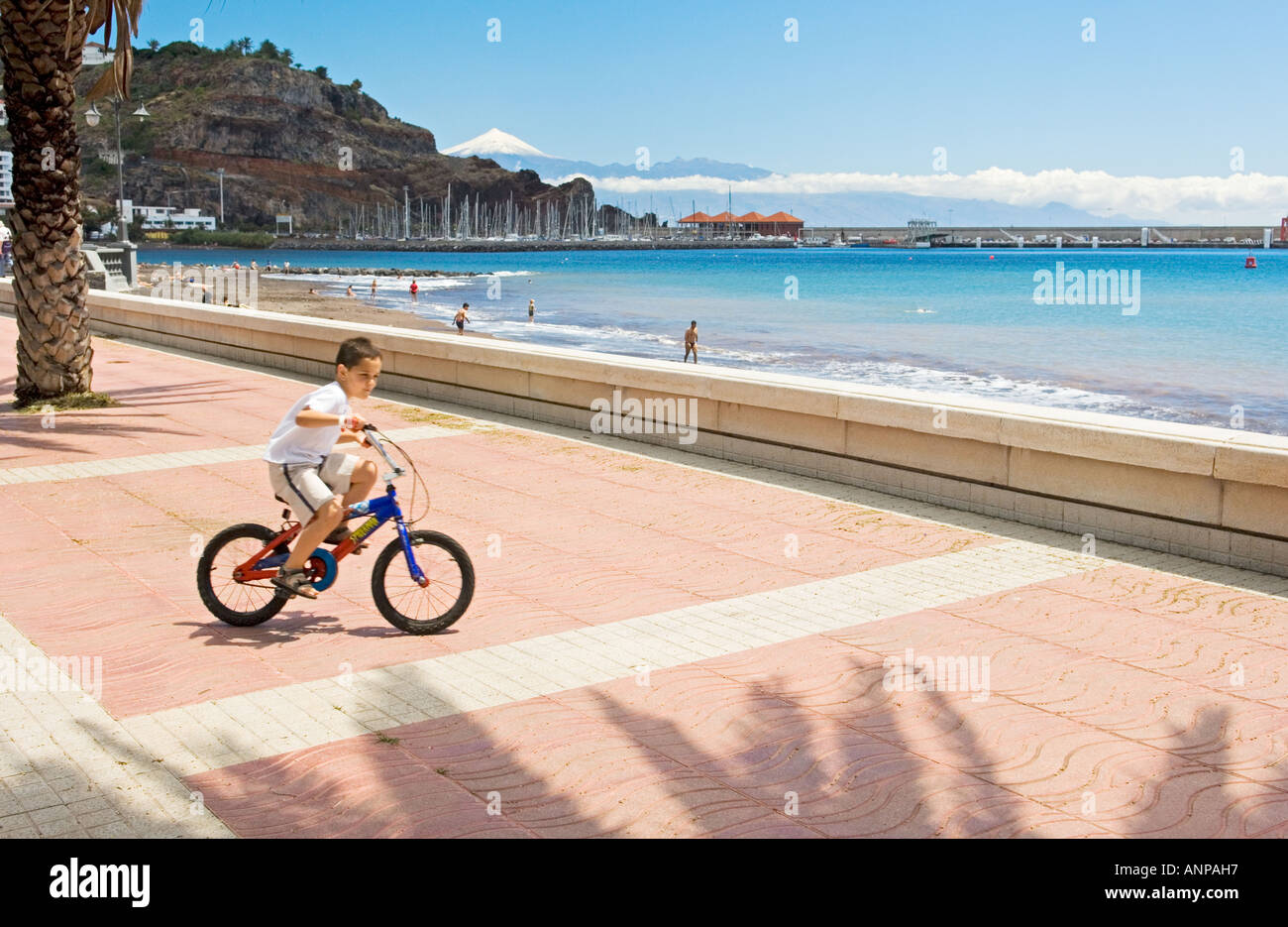 En La Gomera, Islas Canarias. Niño en bicicleta por el paseo de la Playa de  San Sebastián. Nieve pico del Teide en Tenerife detrás Fotografía de stock  - Alamy