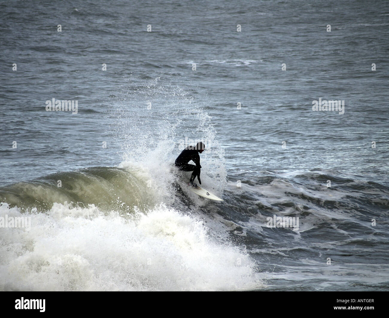 Surfer montando una onda en el invierno de Cornwall, Inglaterra, Reino Unido el 10 de enero de 2008. Foto de stock